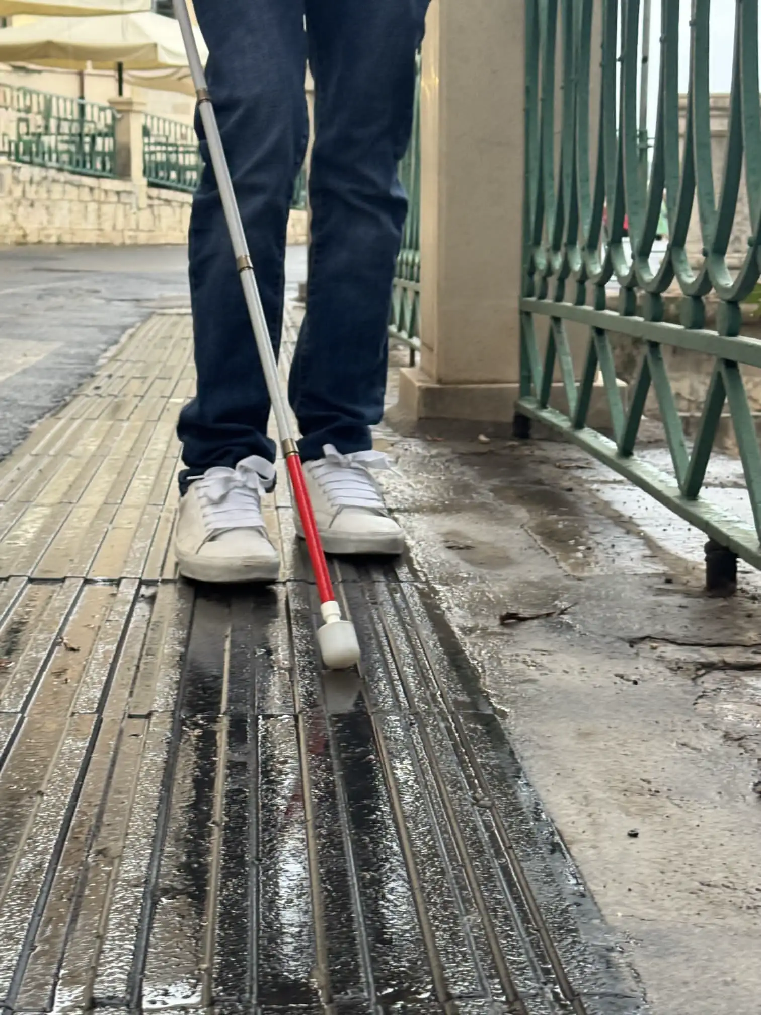 Un'immagine cattura un ragazzo mentre esplora il suo percorso con un bastone per non vedenti.