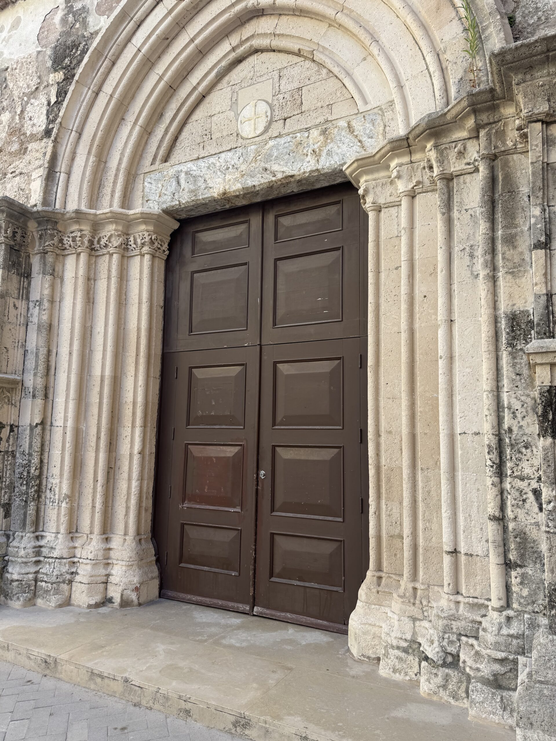 Primo piano del portale gotico della chiesa di San Pietro Apostolo, con le ghiere a sesto acuto e le colonnine verticali in pietra chiara.