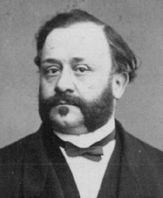 Ritratto in bianco e nero di Gaetano Moscuzza, con barba e baffi, in abito scuro e papillon.