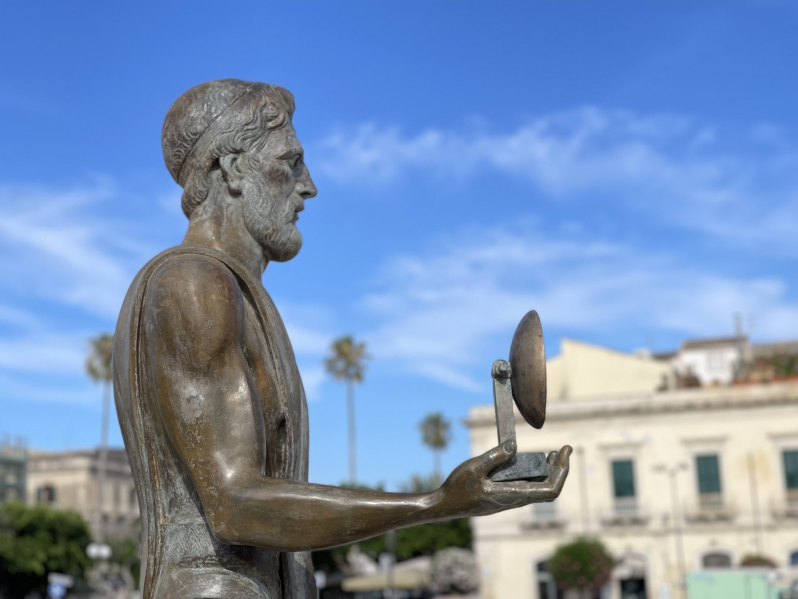Statua bronzea di Archimede con uno specchio in mano.