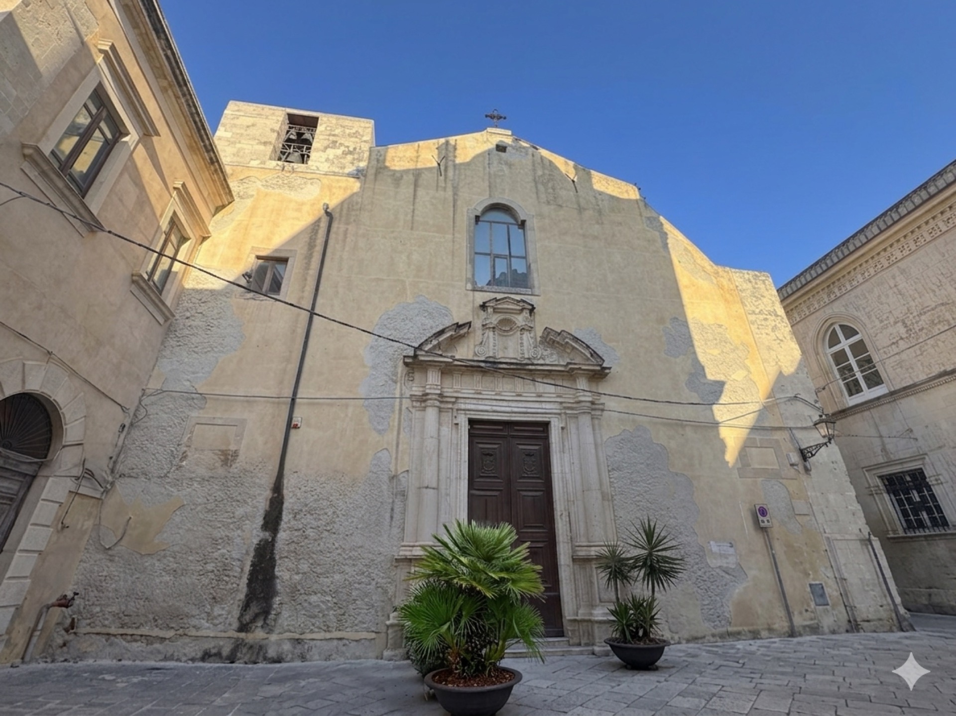 La facciata austera della Chiesa della Madonna del Carmine affacciata sulla Piazzetta del Carmine in Ortigia, con il portale seicentesco del 1602