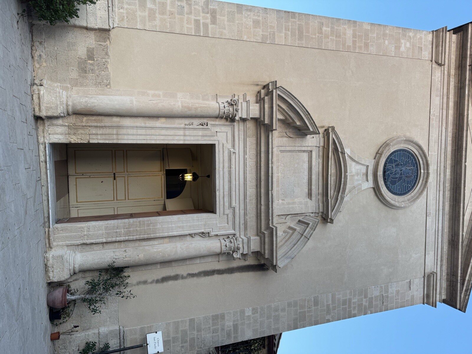 Dettaglio del portale della chiesa di San Paolo Apostolo a Ortigia con colonne corinzie, timpani sovrapposti, iscrizione latina e rosone con vetrata policroma