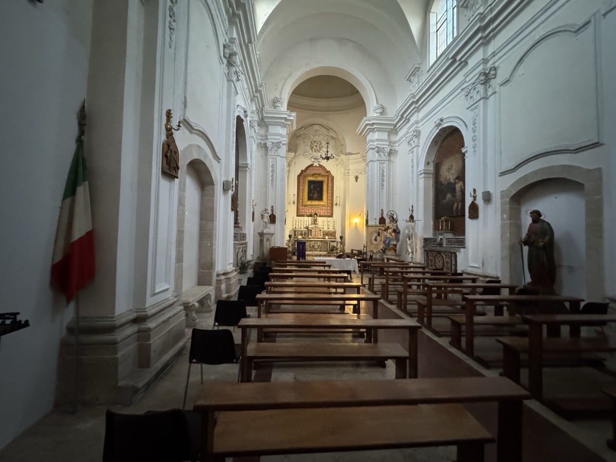 Interno della chiesa di San Paolo Apostolo a Ortigia, navata unica con volta a botte, stucchi geometrici, altari laterali e statua di San Paolo nell'abside