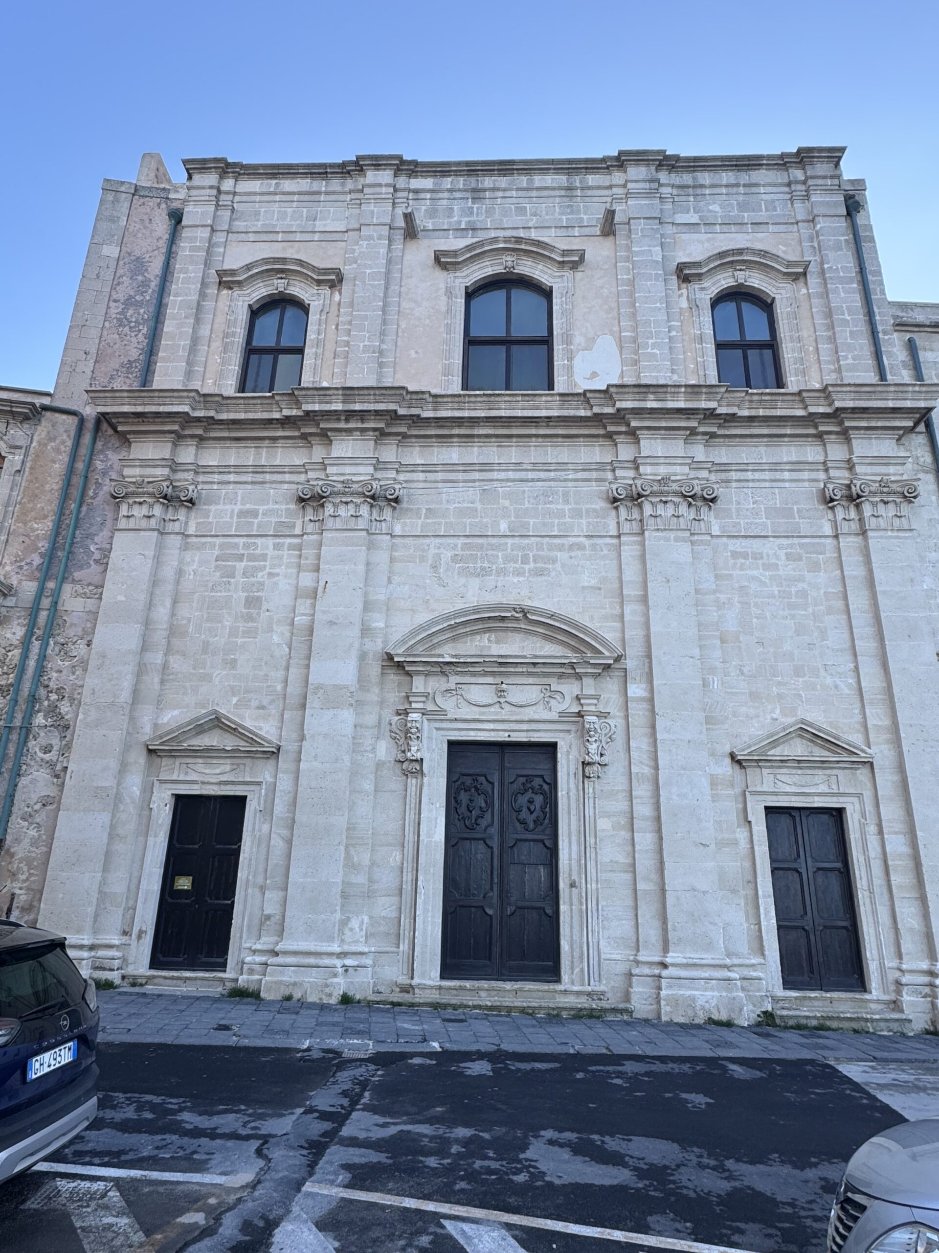 Dettaglio del portale centrale della Chiesa di San Filippo Neri con il timpano ad arco, i mascheroni grotteschi e le decorazioni barocche