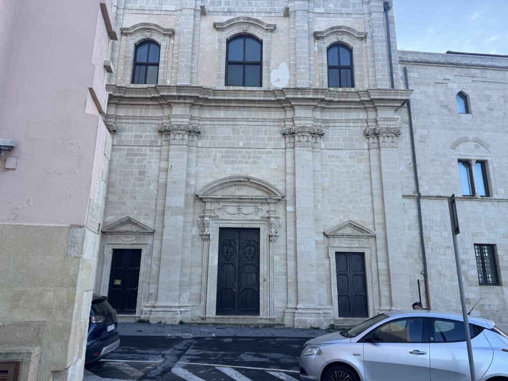 Facciata in pietra con colonne e portoni di una chiesa storica.