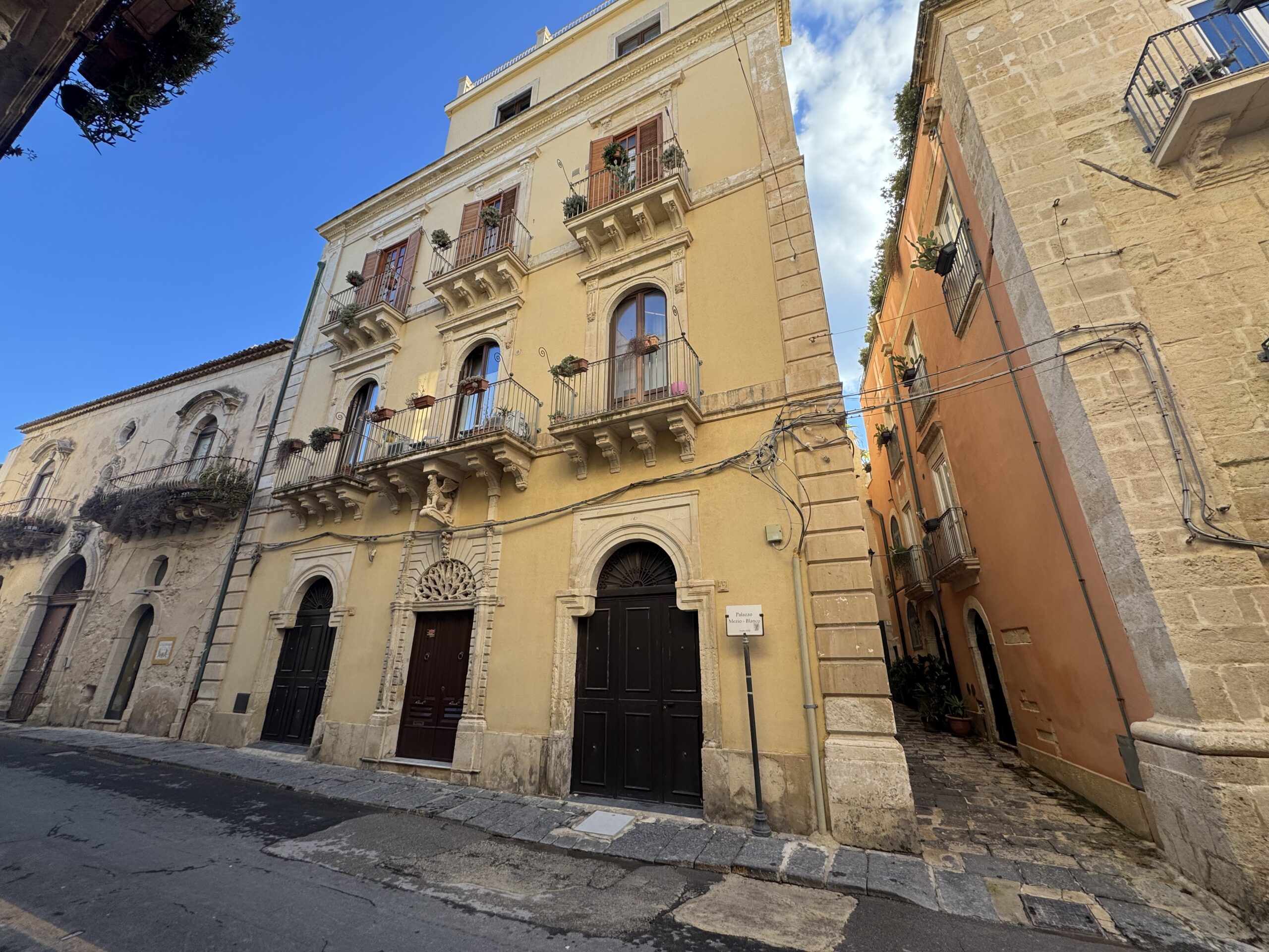 Vista angolare del Palazzo Mezio-Blanco dalla via, con il contesto urbanistico circostante