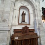 Statua lignea policroma di San Francesco d'Assisi in saio cappuccino, con le braccia aperte e le stigmate alle mani, collocata in una nicchia con cornice in pietra iblea sopra un mobile in legno settecentesco