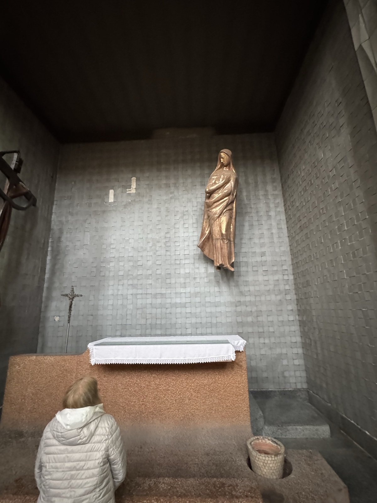 Cappella agostiniana con scultura dorata di monaca (santa Monica o Madonna Addolorata) su parete a mosaico grigio e altare in marmo