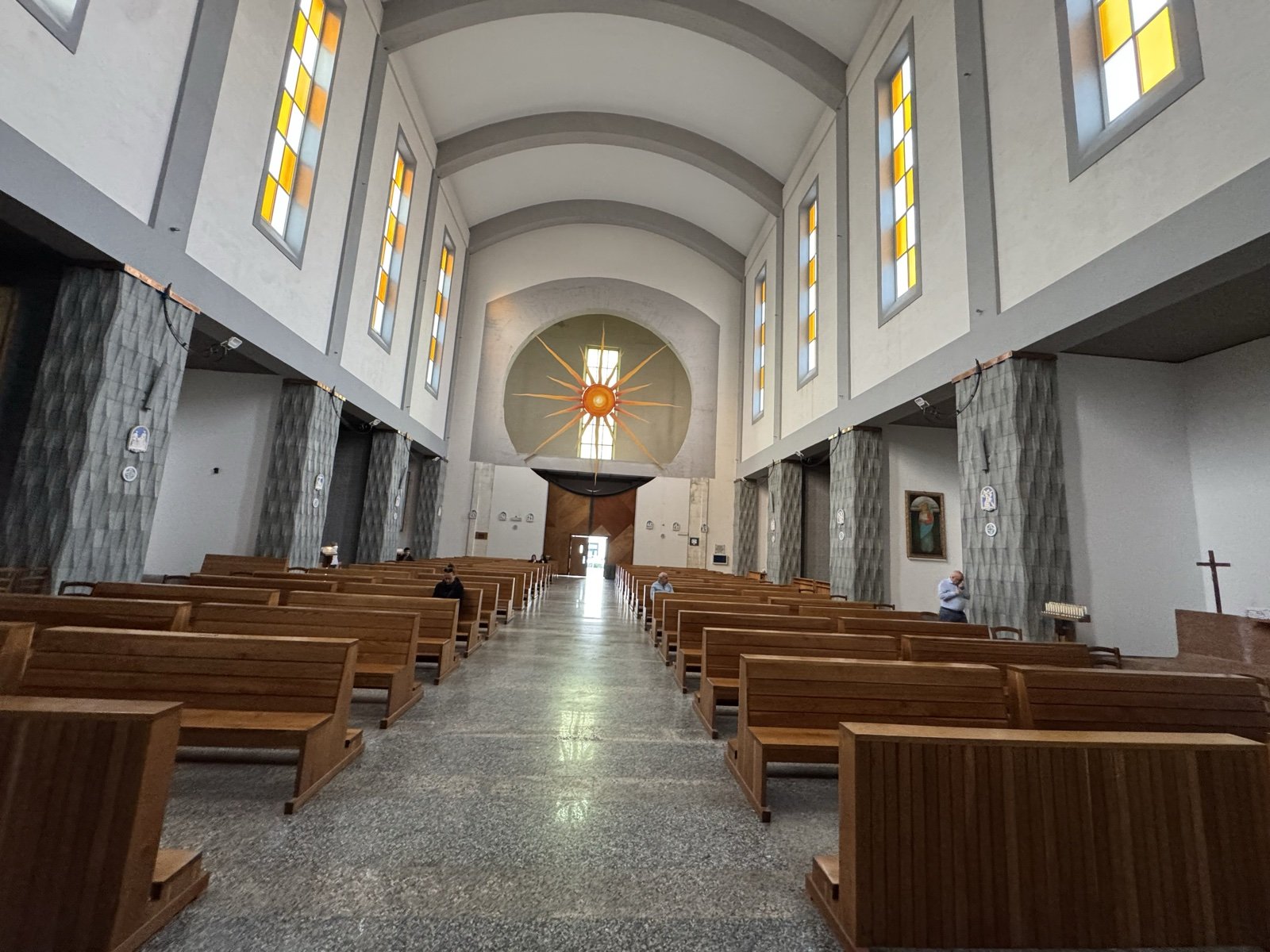 Interno della Chiesa di Santa Rita a Siracusa: controfacciata vista dall'altare con arco contenente la raggiera del sole e la vetrata verticale che illumina la navata