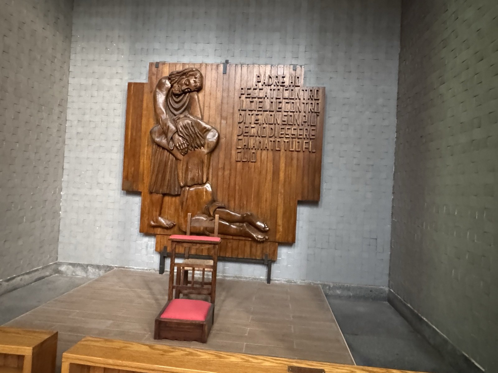 Altorilievo ligneo del Figliol prodigo nella Chiesa di Santa Rita a Siracusa: tre pannelli in legno scolpito con figura in ginocchio, figura giacente a terra e testo biblico