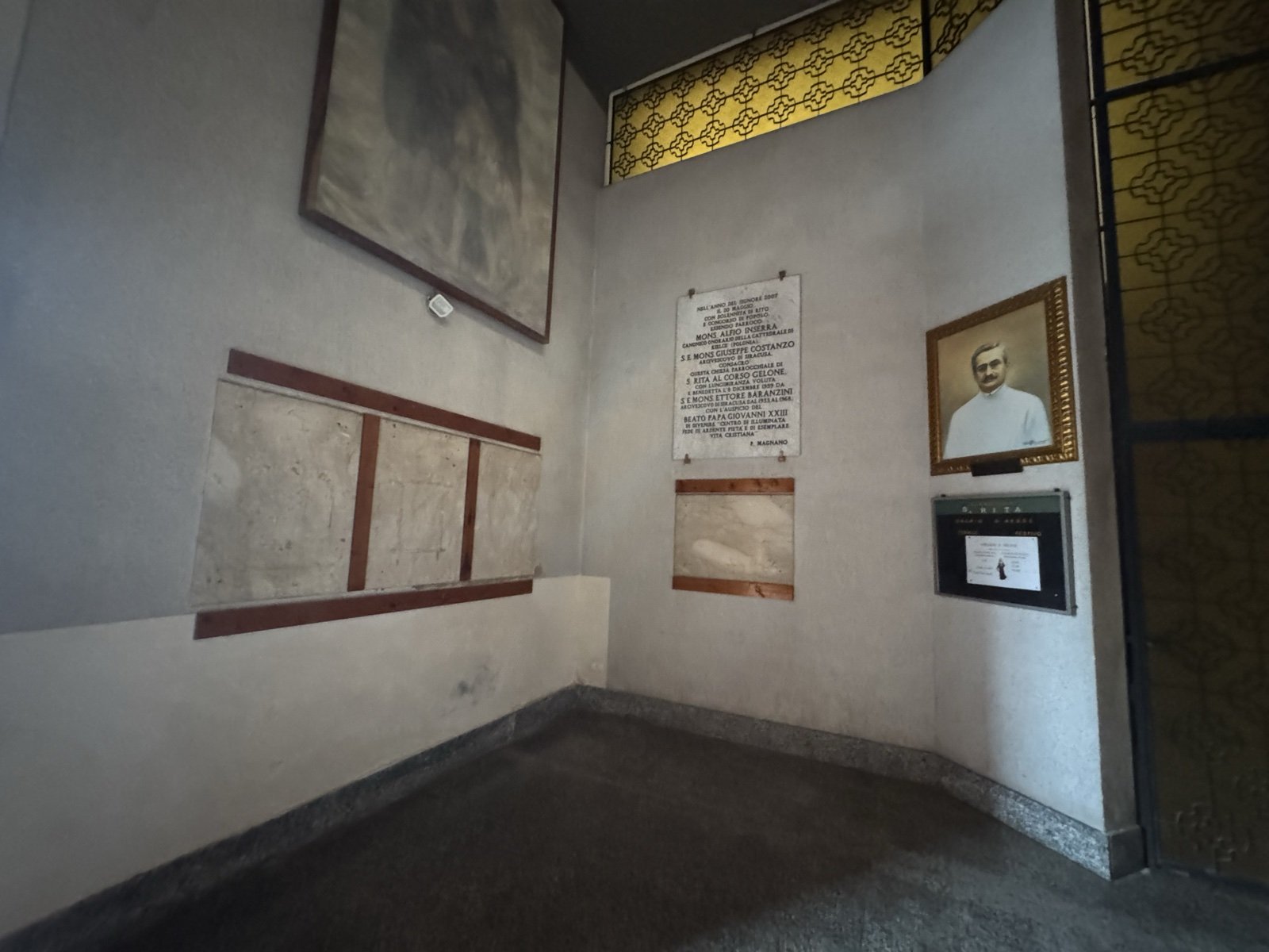 Lapide della consacrazione della Chiesa di Santa Rita a Siracusa: marmo bianco con iscrizione in lettere dorate, ritratto di Mons. Alfio Inserra e frammenti antichi di affreschi murati