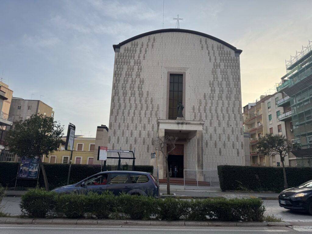 Edificio moderno con facciata decorata e statua in alto.