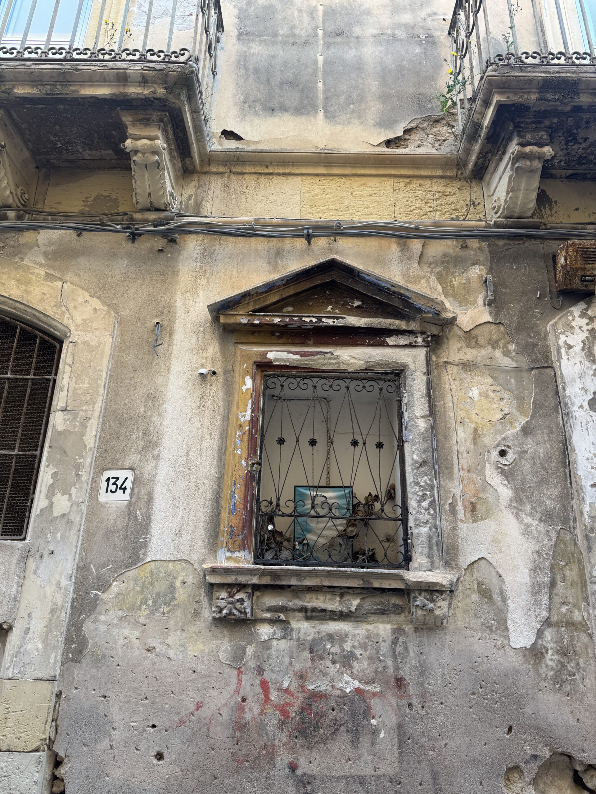 Vista verticale dell'edicola votiva di Via Dione 134, con il timpano triangolare e la facciata degradata