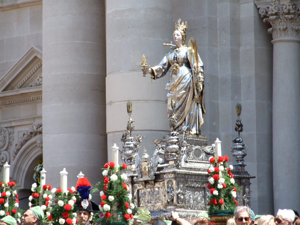 Statua argentea di Santa Lucia su un carro decorato.