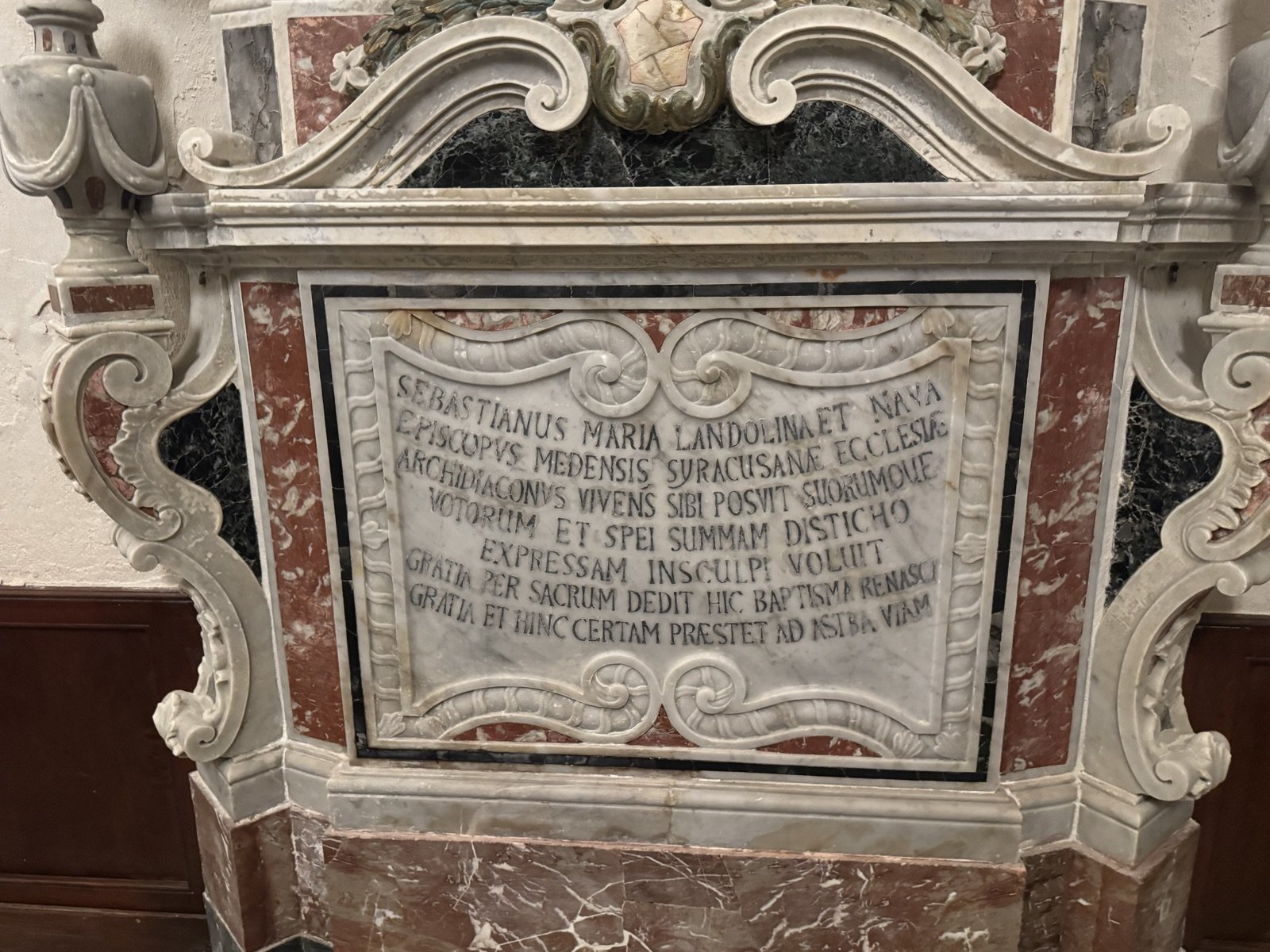 Lapide marmorea barocca del vescovo Sebastiano Maria Landolina e Nava con cornice in marmi policromi e stemma vescovile sommitale