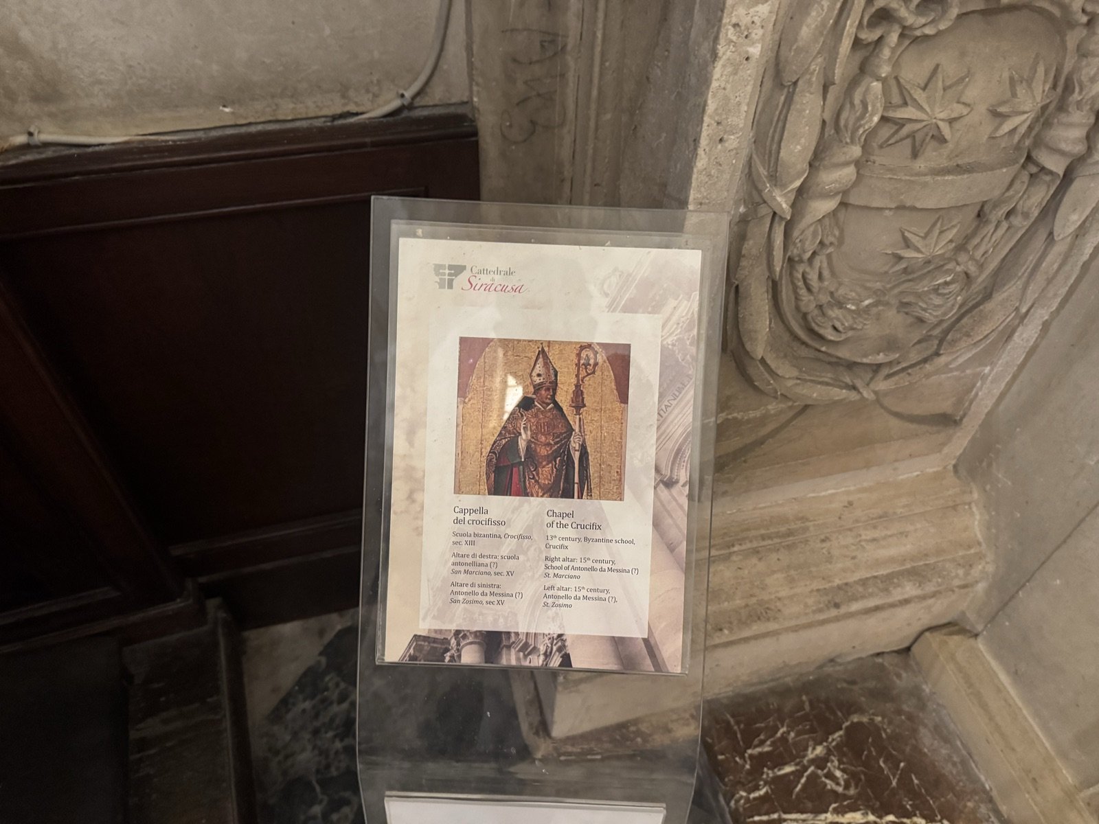 Pannello informativo bilingue della Cattedrale di Siracusa che descrive la Cappella del Crocifisso: Crocifisso bizantino XIII secolo, San Marciano scuola antonelliana XV secolo, San Zosimo Antonello da Messina XV secolo