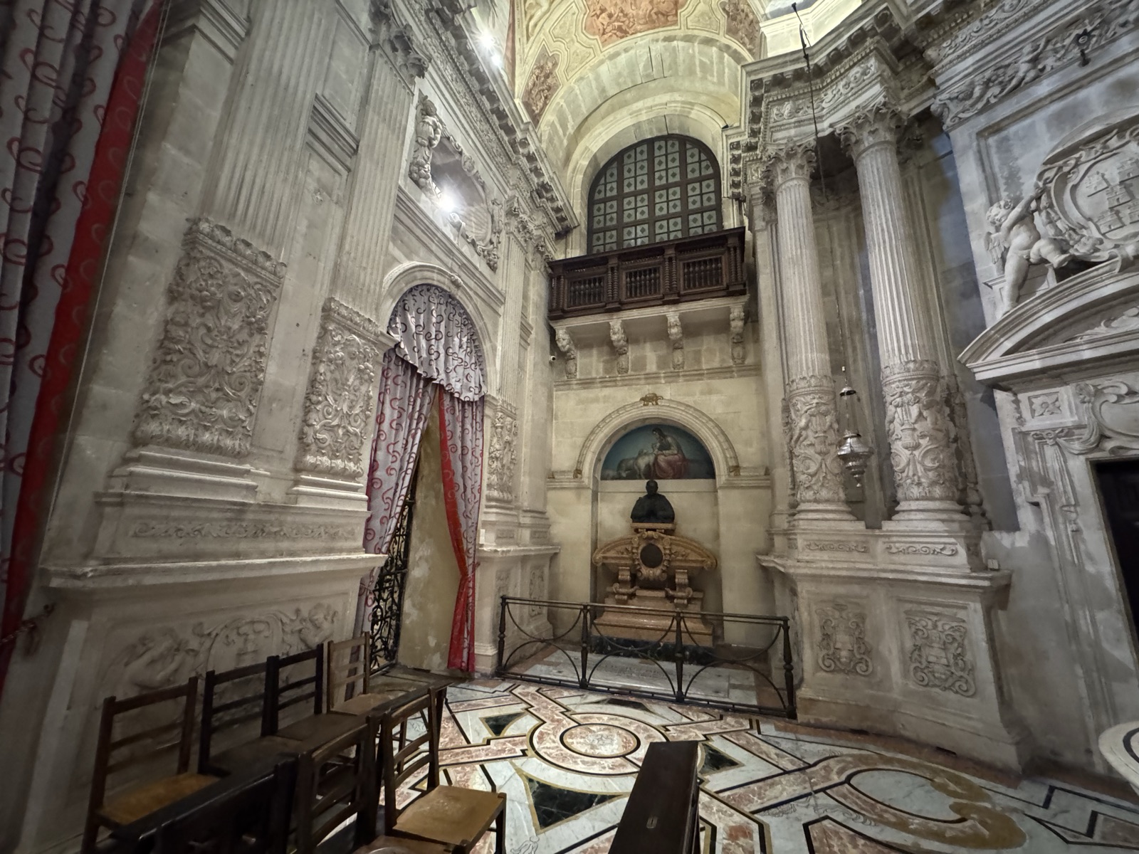 Uno dei portali laterali della Cappella del Santissimo Sacramento del Duomo di Siracusa con cancello in ferro battuto di Domenico Ruggeri 1807-1811 e tendaggio in tessuto rosso e oro