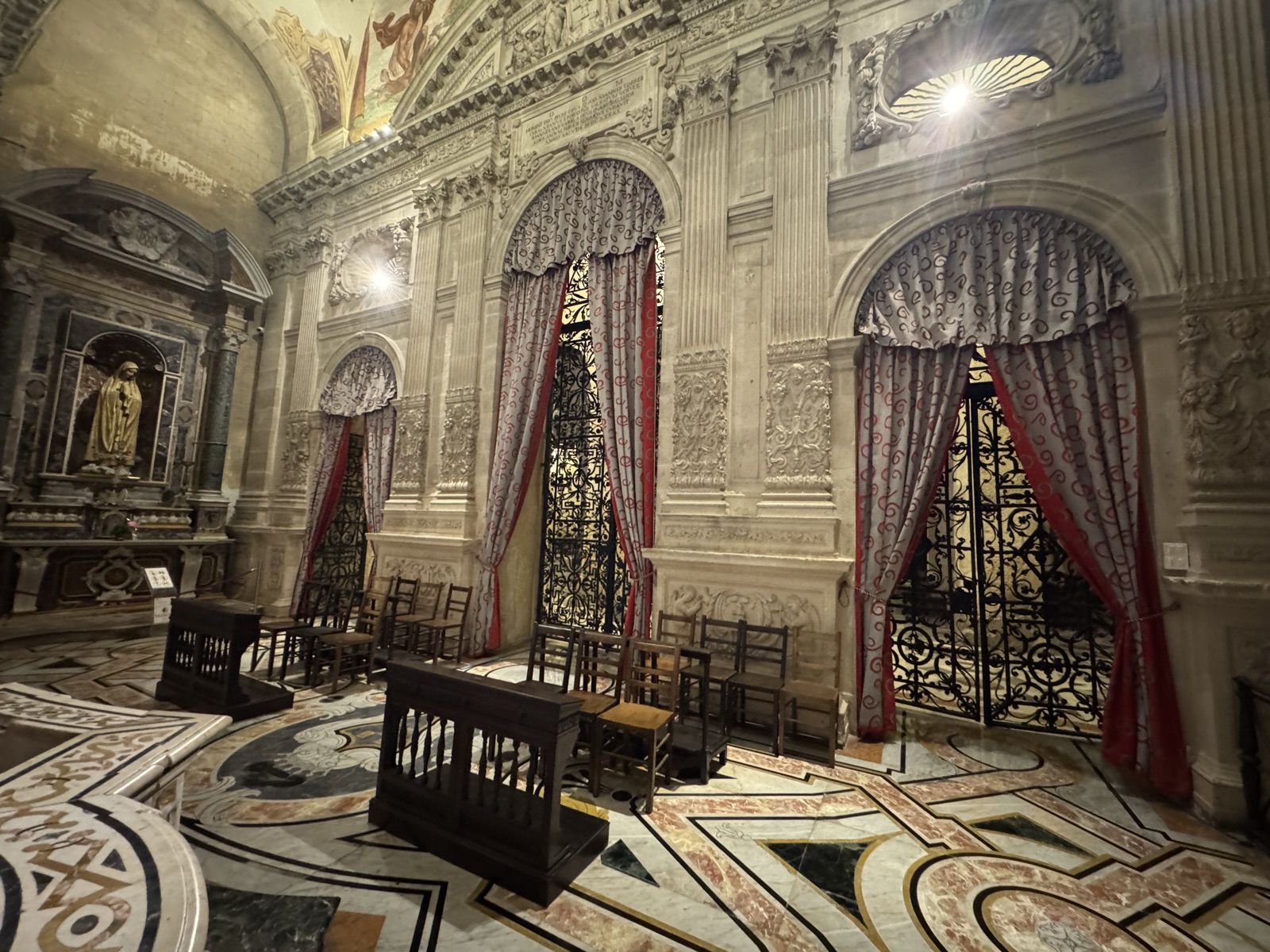 Vista d'insieme dell'interno della Cappella del Santissimo Sacramento con tre portali laterali chiusi da tendaggi rossi e oro, pianta ottagonale dei Vermexio, pavimento in marmi policromi