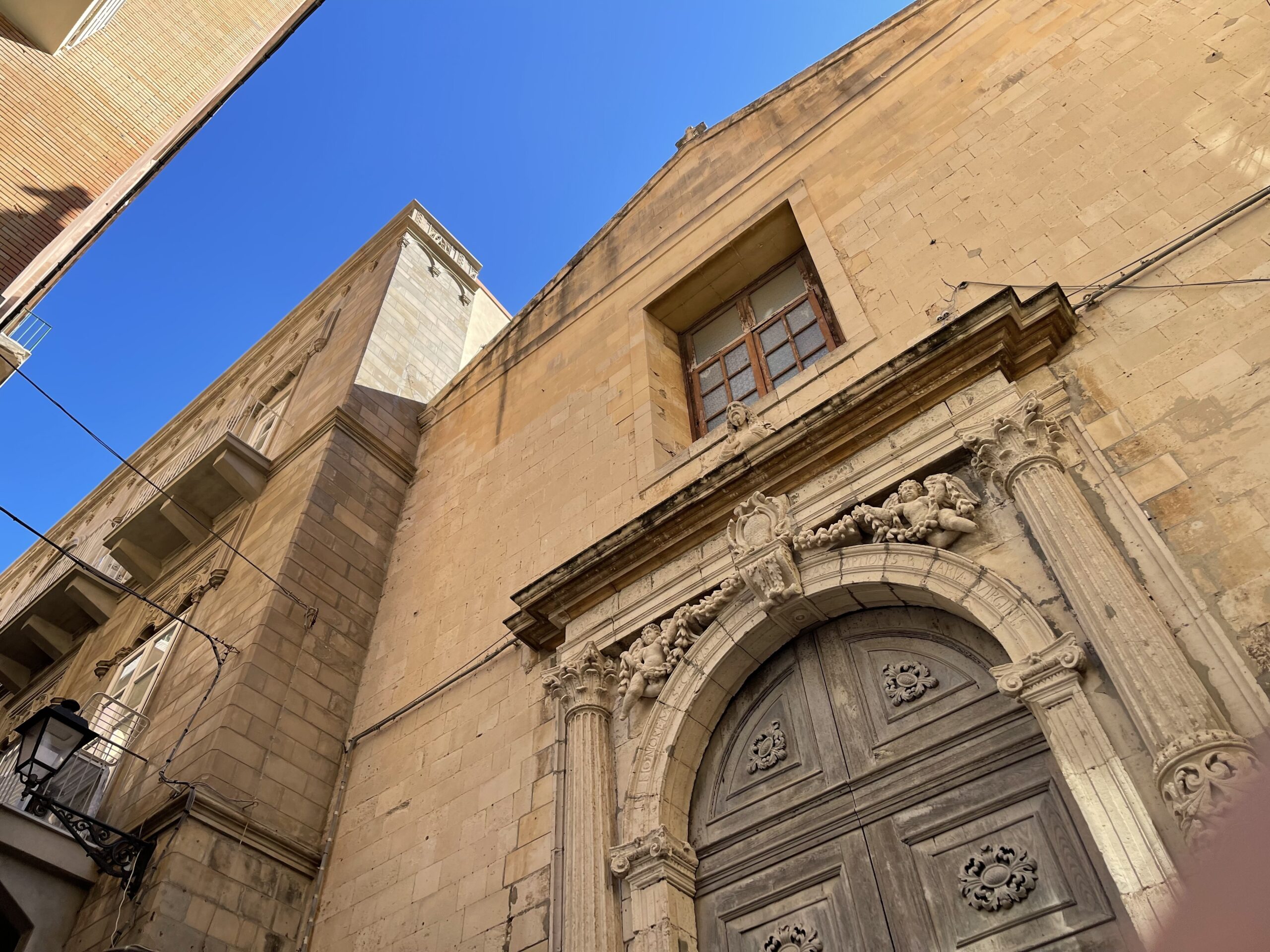 Dettaglio del portale barocco con cornice di motivi floreali e busto di San Cristoforo