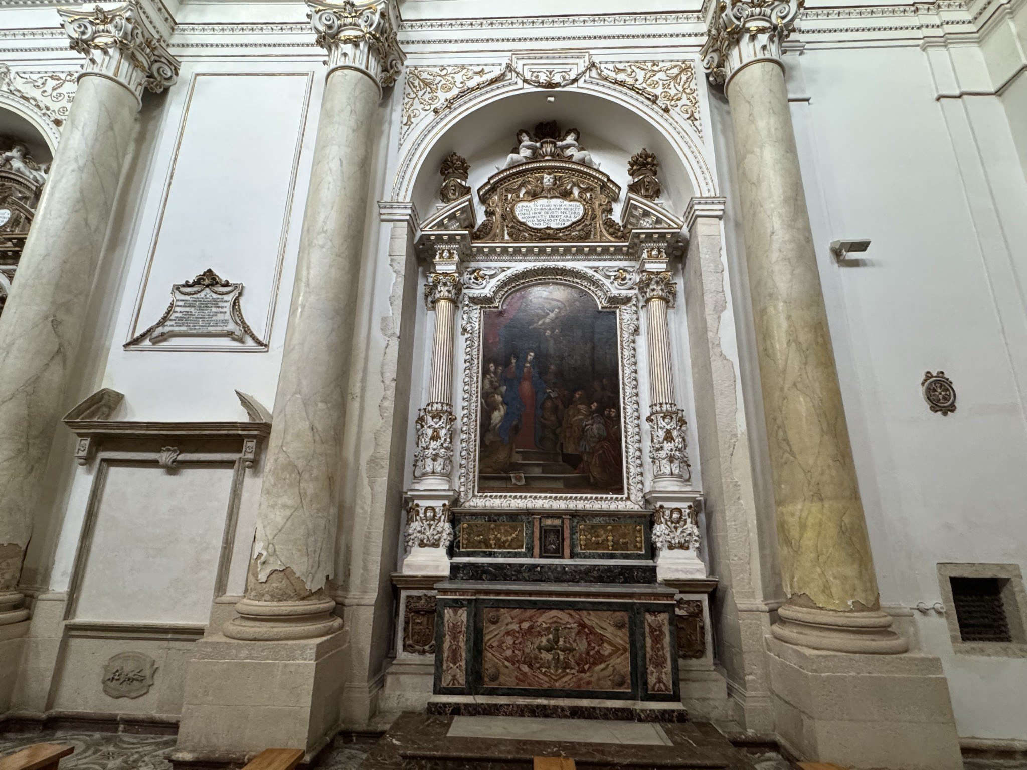 Altare laterale con pala devozionale, cornice modanata bianca e dorata, paliotto in marmi mischi e mensa decorata.