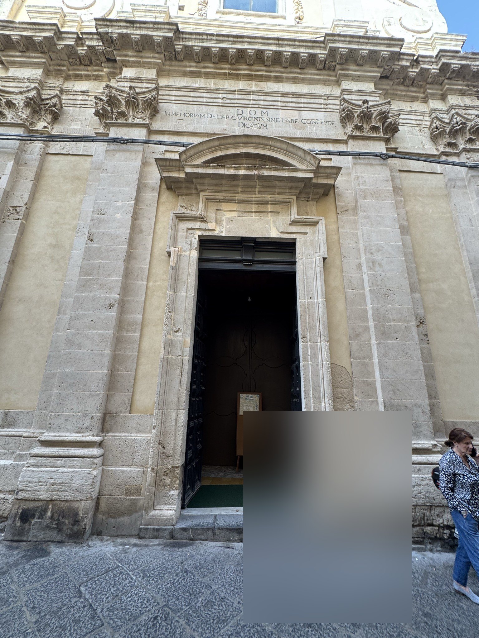 Epigrafe lapidea D.O.M. collocata sopra il portale d'ingresso, all'interno di una cornice modanata in pietra calcarea.