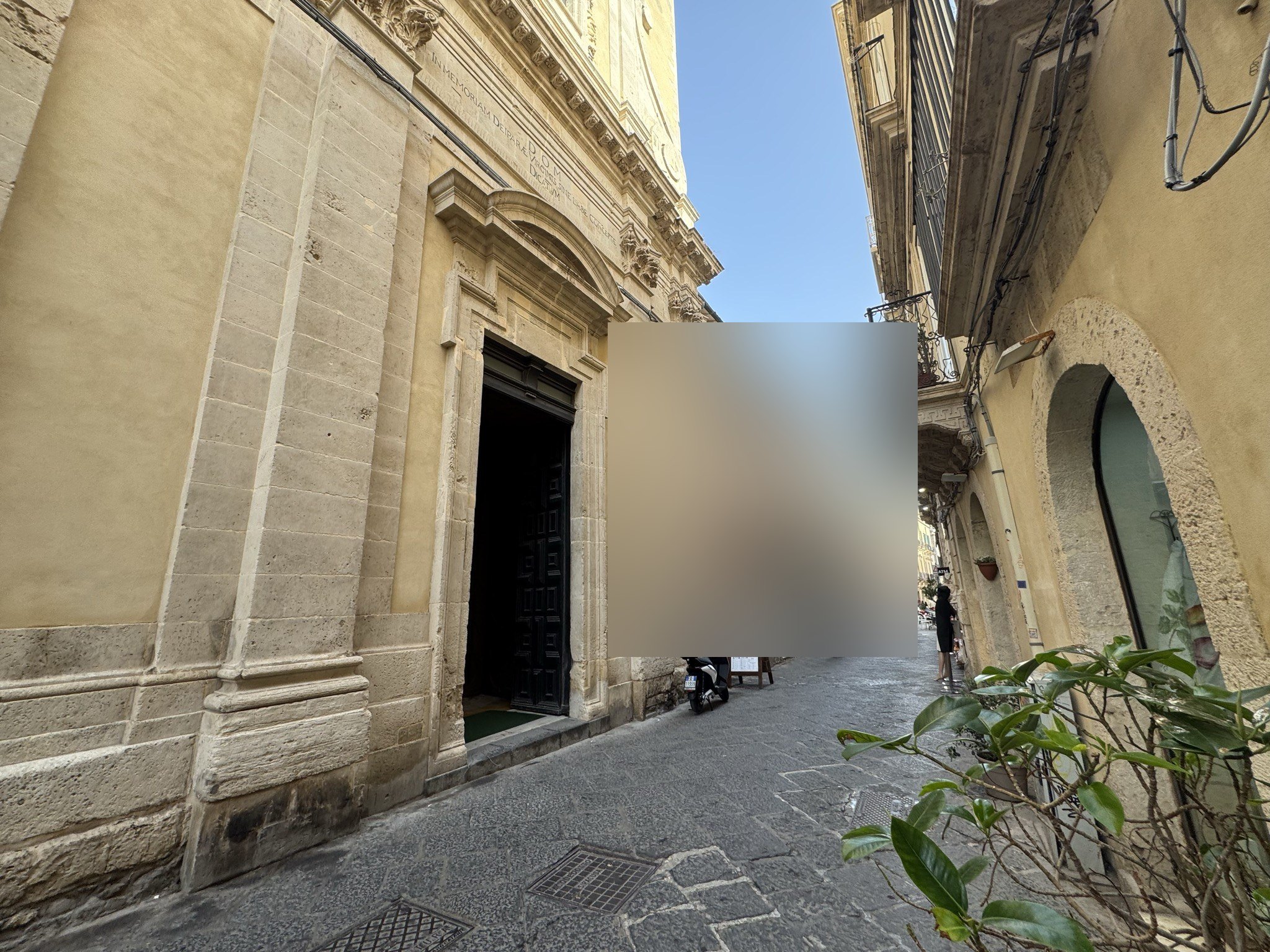 Scorcio del fianco della chiesa lungo via Roma a Ortigia, con il portale laterale chiuso e il filo continuo del paramento murario.