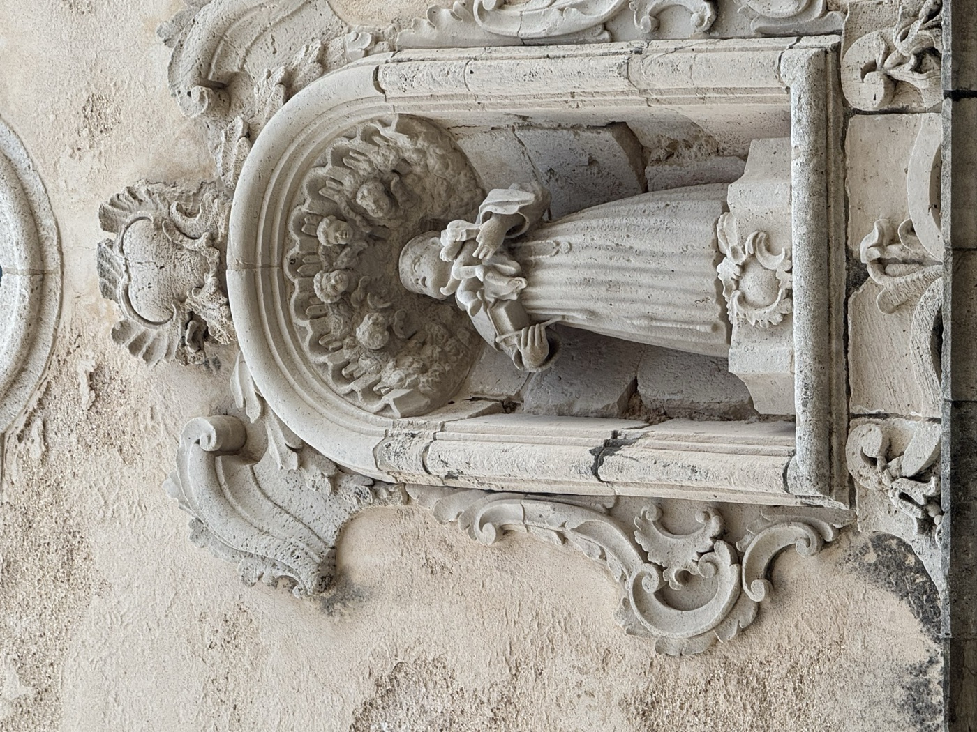 Vista laterale ravvicinata dell'edicola di Sant'Antonio di Padova in via Vittorio Veneto 41 Ortigia con cornice barocca scolpita a volute e cartocci