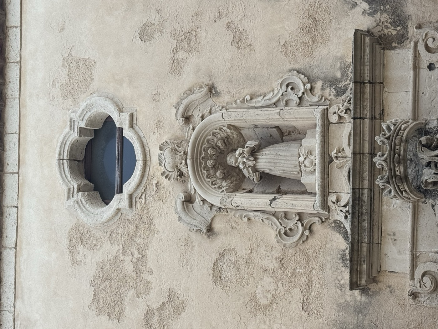 Oculus mistilineo polilobato in pietra calcarea soprastante l'edicola di Sant'Antonio di Padova in via Vittorio Veneto 41 Ortigia