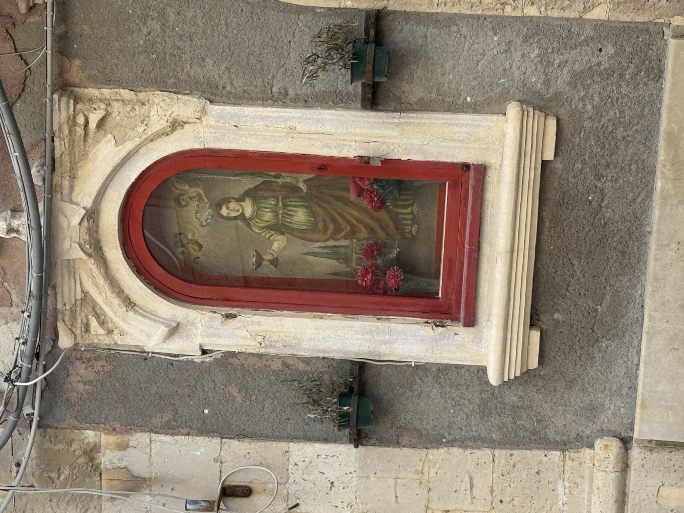 Cornice in pietra calcarea bianca dell'edicola di Santa Lucia con lesene laterali scanalate aperte a orecchioni superiori, arco a tutto sesto, base modanata e coronamento