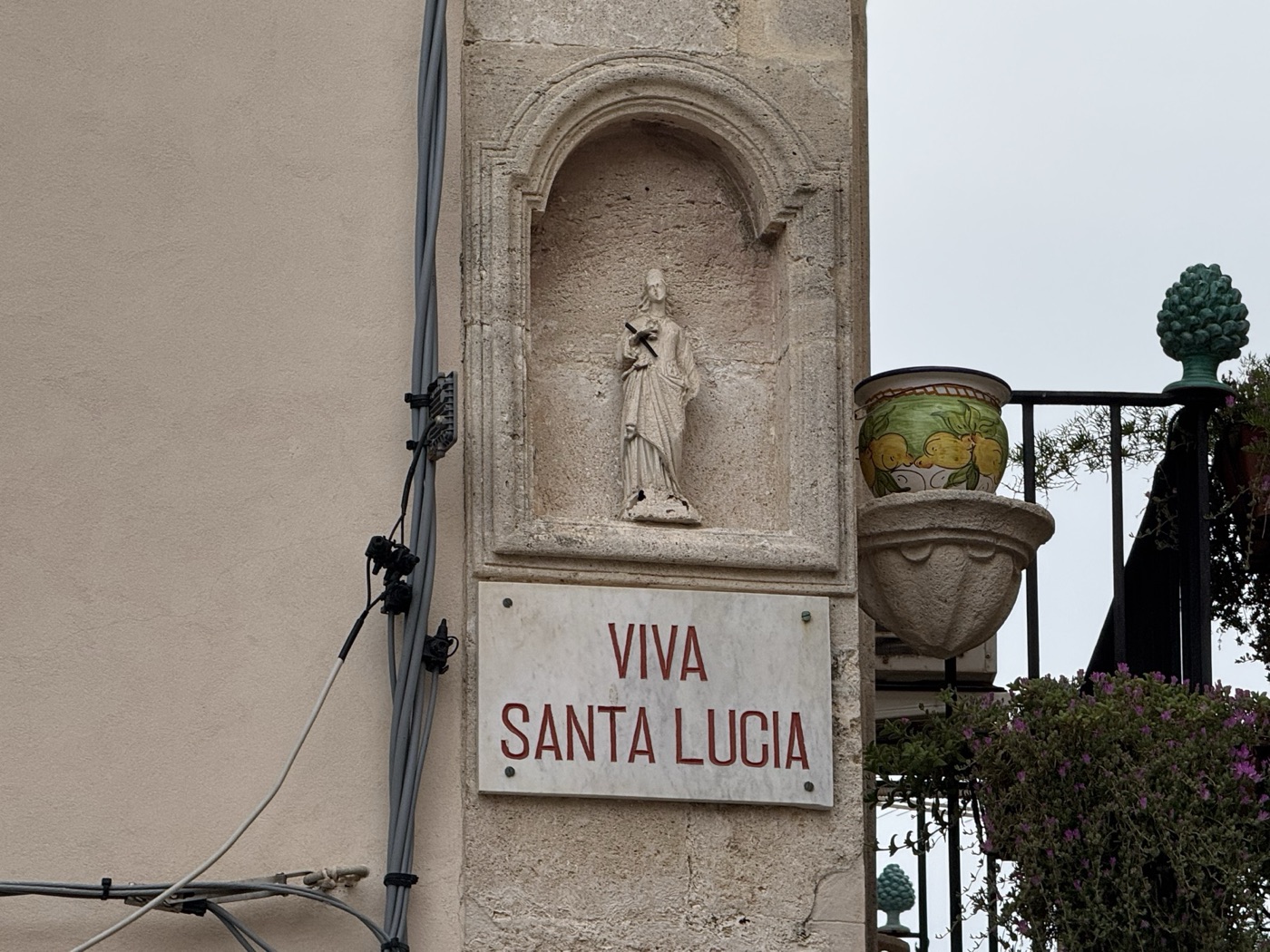 Edicola votiva di Santa Lucia sul cantonale tra via Pompeo Picherali e piazzetta San Rocco a Ortigia con statua in pietra calcarea nella nicchia e lapide marmorea VIVA SANTA LUCIA sottostante