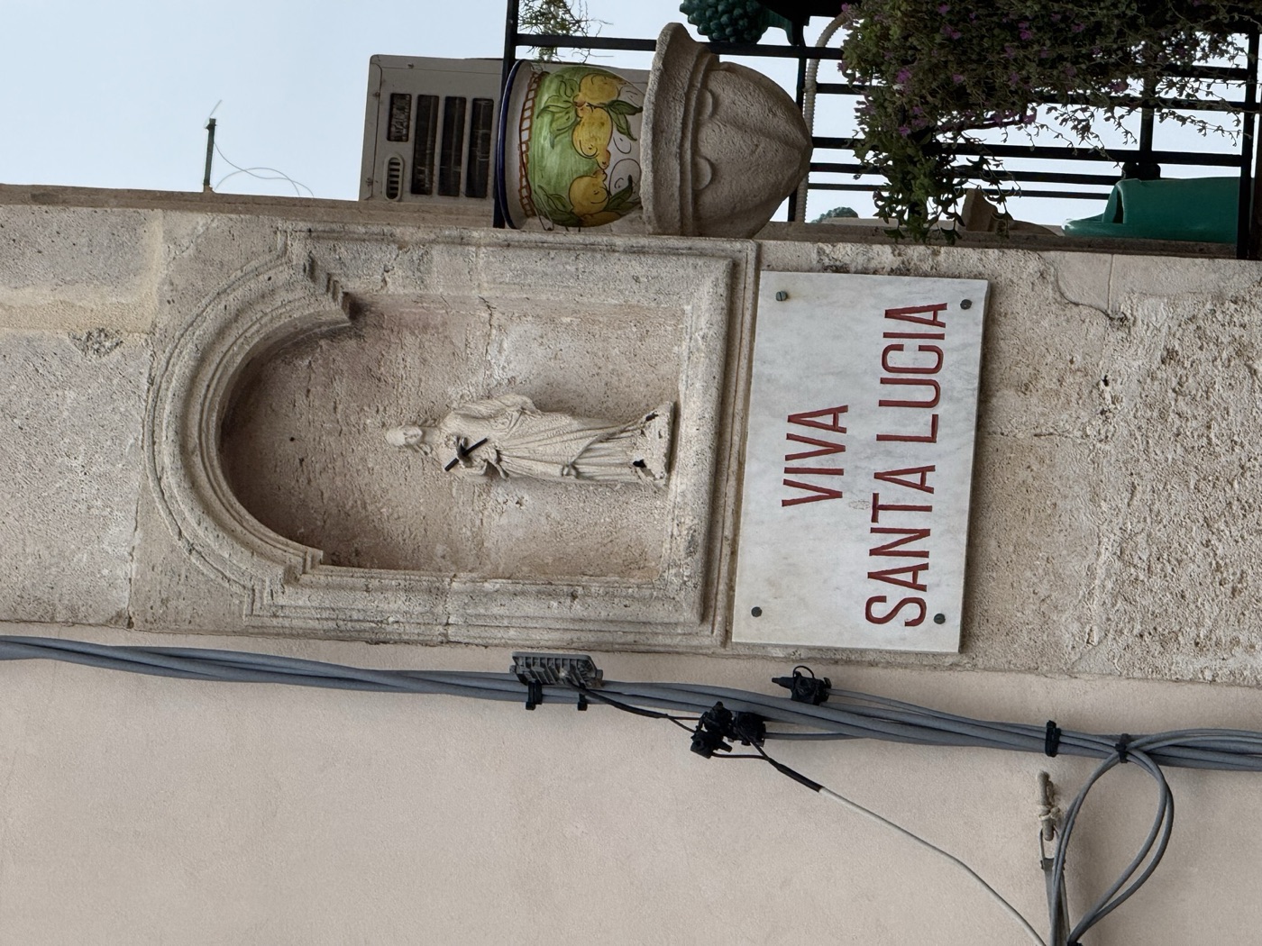 Lapide marmorea con iscrizione devozionale VIVA SANTA LUCIA in lettere rosse sotto la nicchia dell'edicola in pietra calcarea del cantonale piazzetta San Rocco via Picherali Ortigia