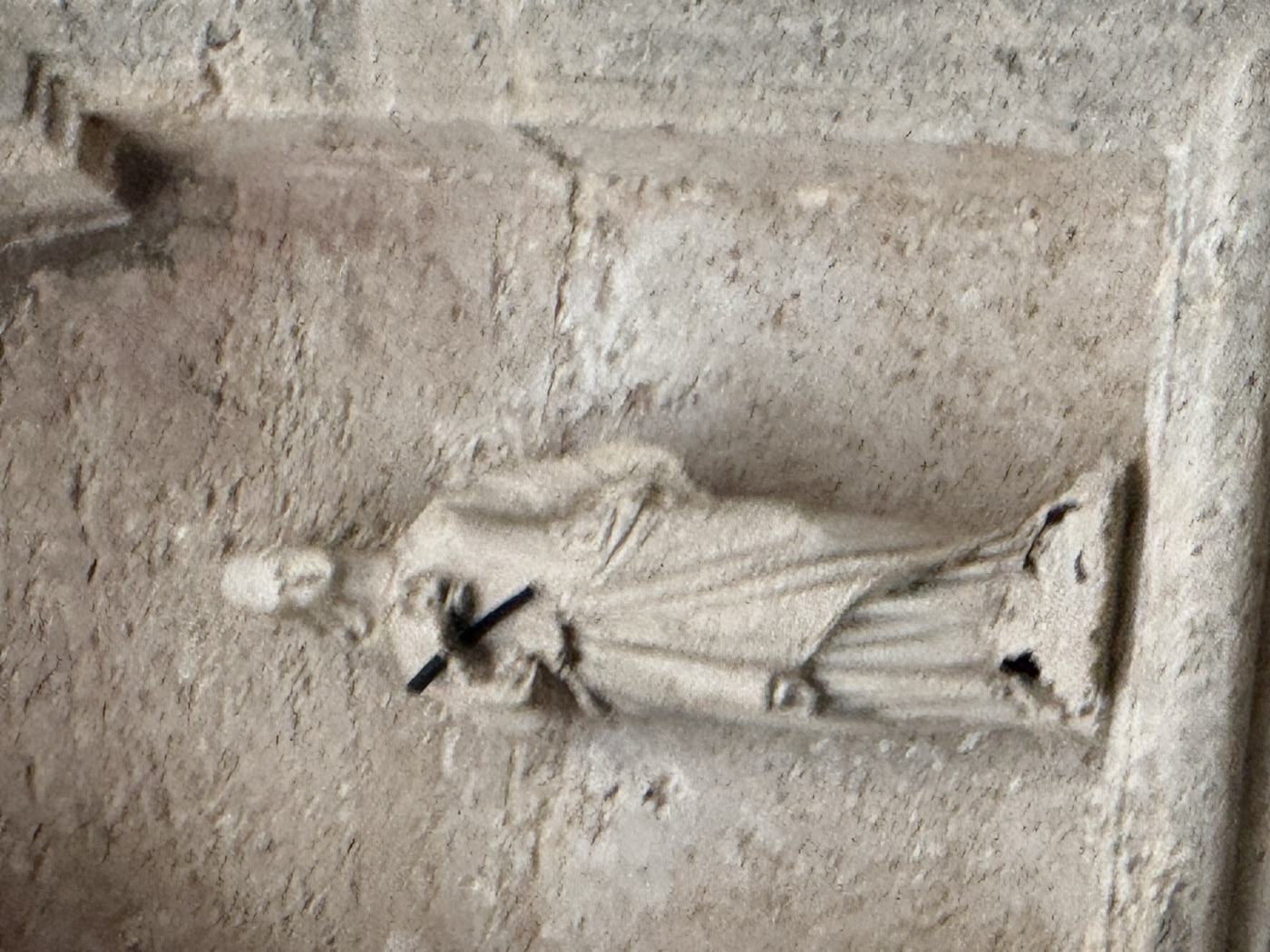 Macro ravvicinato della statua scolpita in pietra calcarea di Santa Lucia con palma del martirio diagonale al petto nelledicola del cantonale piazzetta San Rocco Ortigia