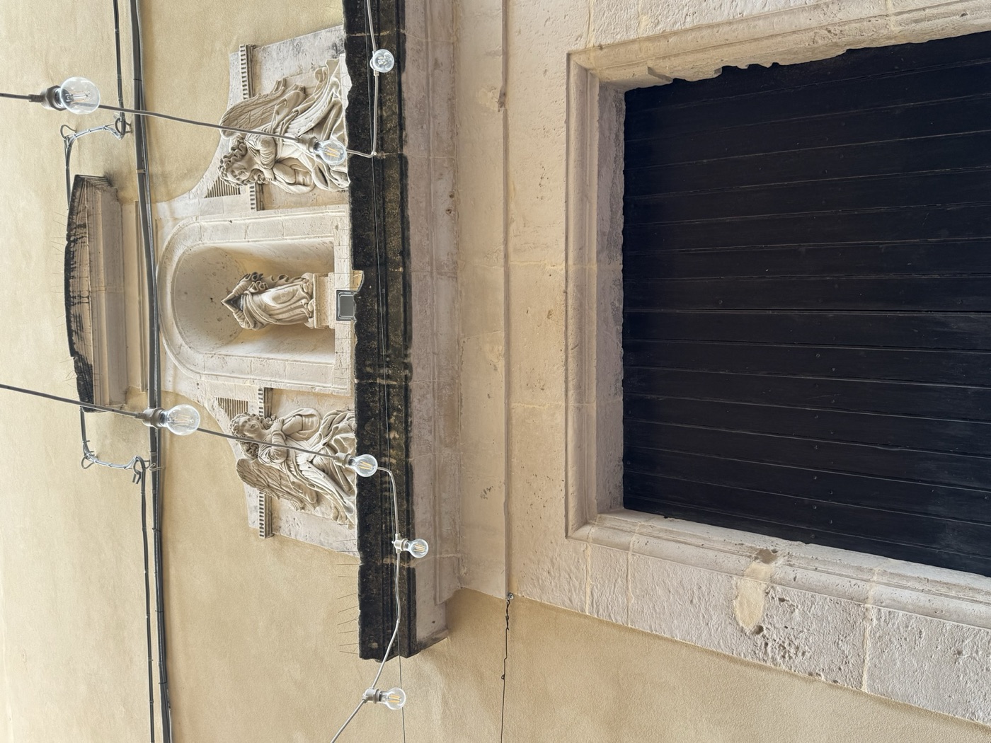 Edicola di Sant'Antonio di Padova in via Vittorio Veneto 41 con i cavi e fili elettrici e telefonici fissati alla facciata e l'oculus polilobato visibile in alto