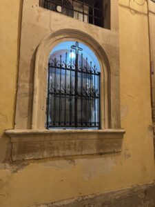 Edicola votiva del Crocifisso, scorcio notturno con la grata in ferro battuto e la croce centrale in controluce