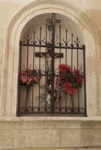 L'edicola del Crocifisso a Ortigia in una documentazione anteriore al 2021: nicchia con Crocifisso ligneo a tutto tondo policromo e fiori rossi votivi
