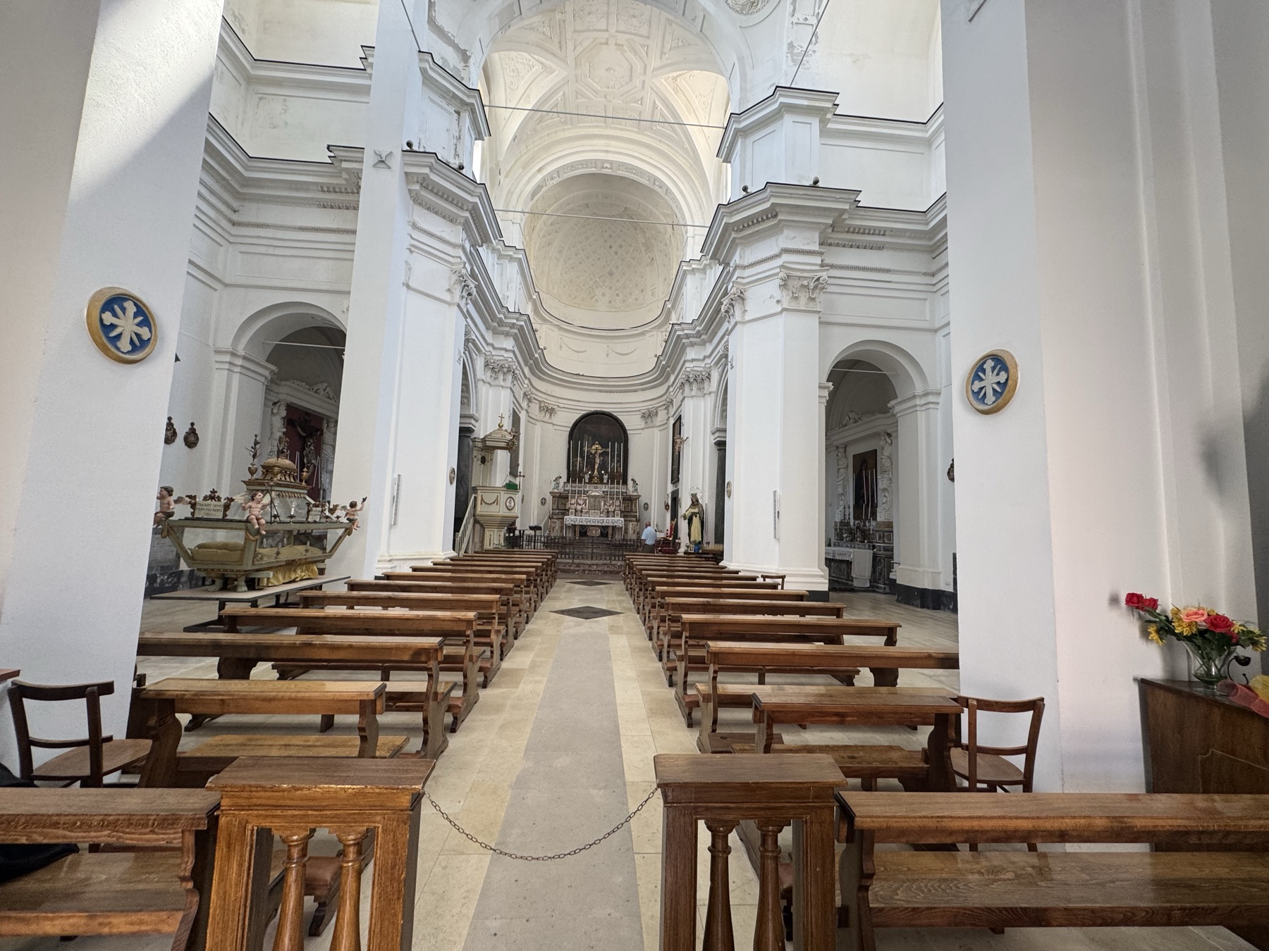 Navata centrale della chiesa con pilastri bianchi, archi a tutto sesto, tondi decorativi azzurri sulle pareti laterali e abside sullo sfondo.
