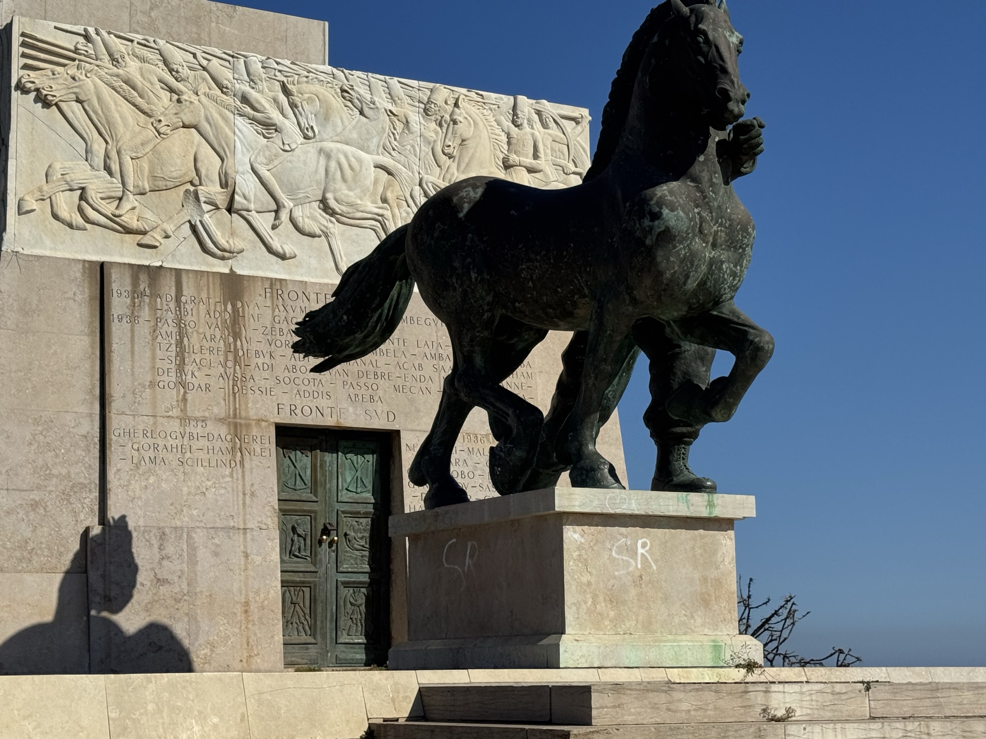 Cavallo bronzeo accanto al portale d'ingresso del monumento e iscrizioni con i nomi delle località dei fronti nord e sud della campagna d'Etiopia 1935-36