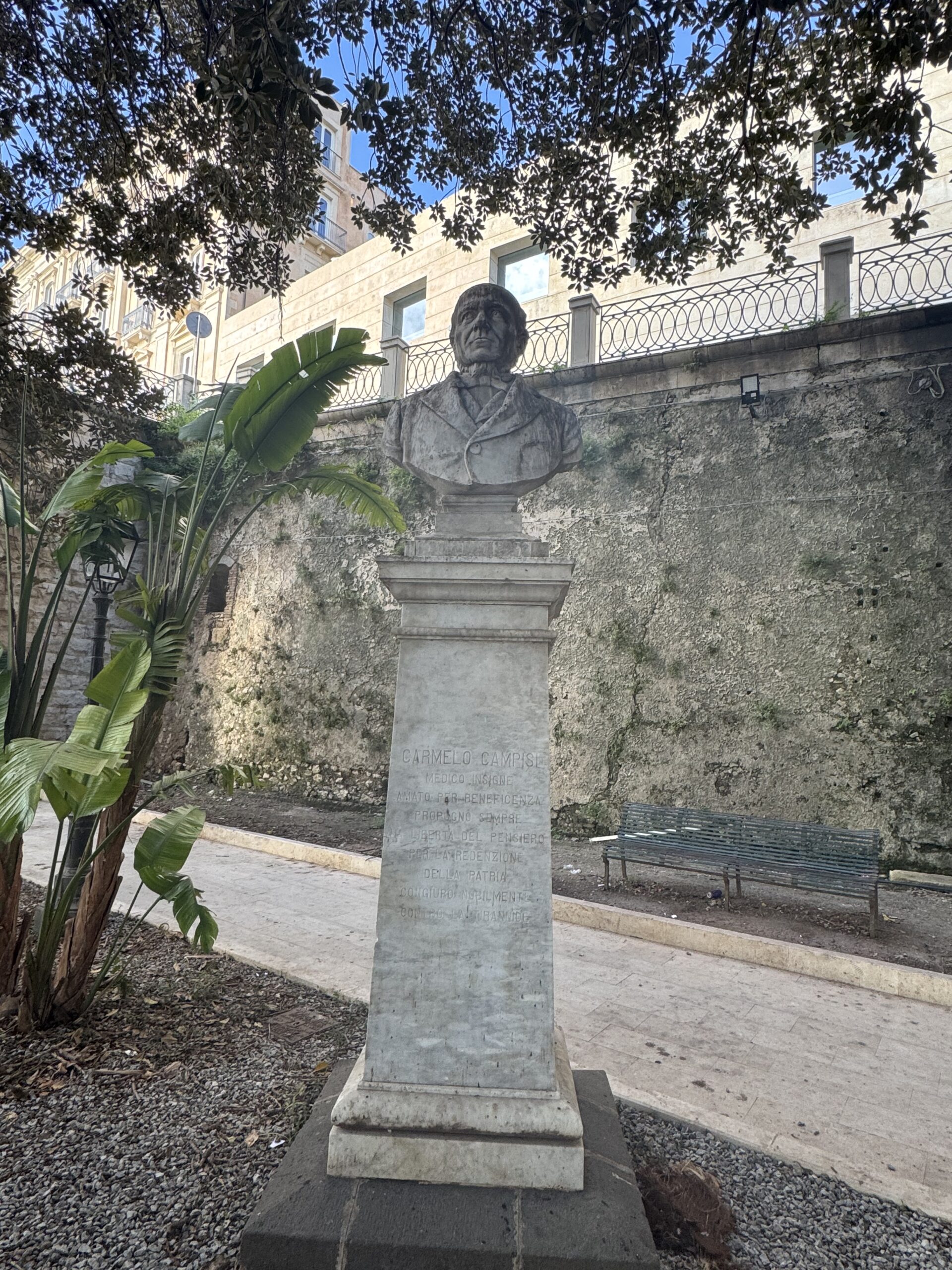Piedistallo del monumento a Carmelo Campisi visto di profilo, articolato in zoccolo, dado liscio e cornice modanata.