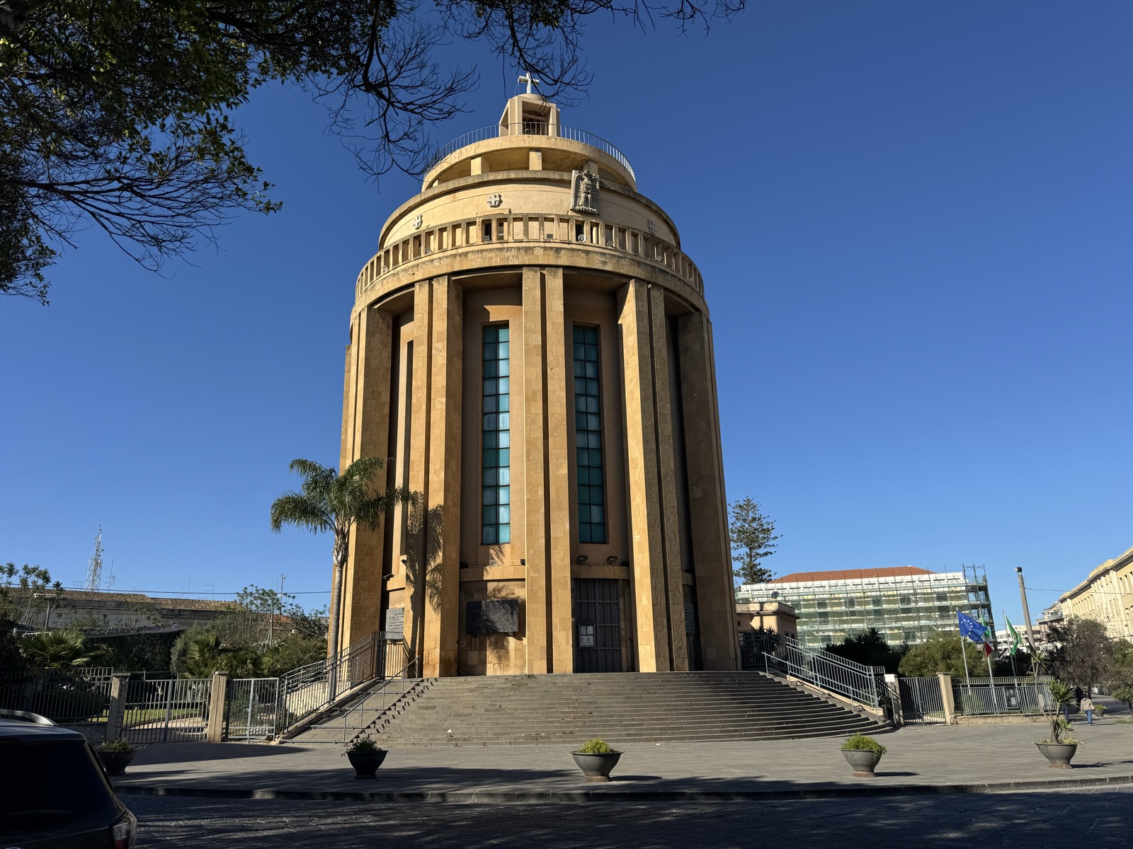 Facciata principale del Pantheon dei Caduti di Siracusa: edificio circolare in cemento armato con doppie file di pilastri verticali, vetrate, cupola con tamburo e croce sulla sommità.