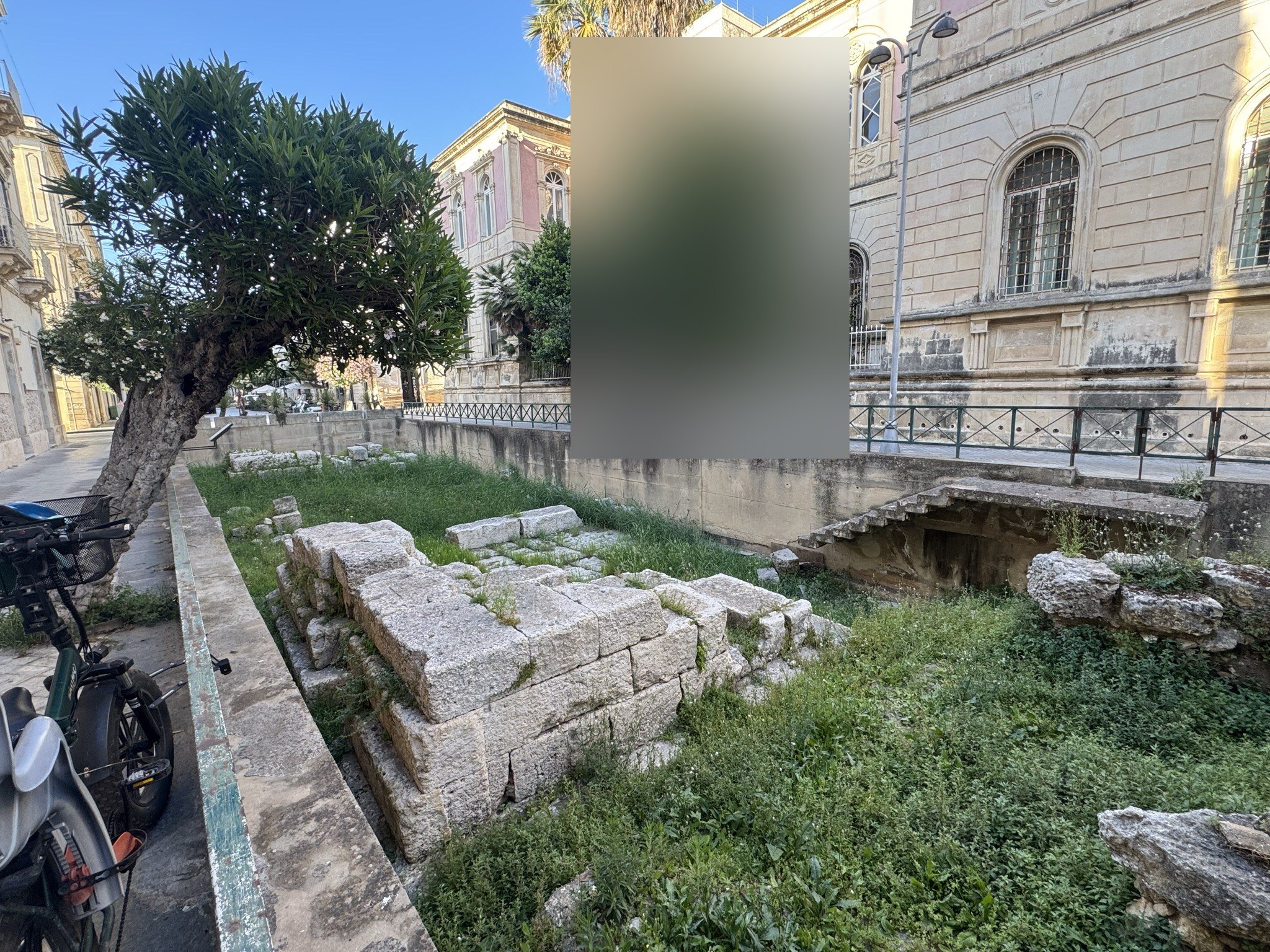Vista ravvicinata dei blocchi squadrati in calcare bianco della soglia della Porta Urbica di Siracusa, con accenno di gradino in pietra a destra.