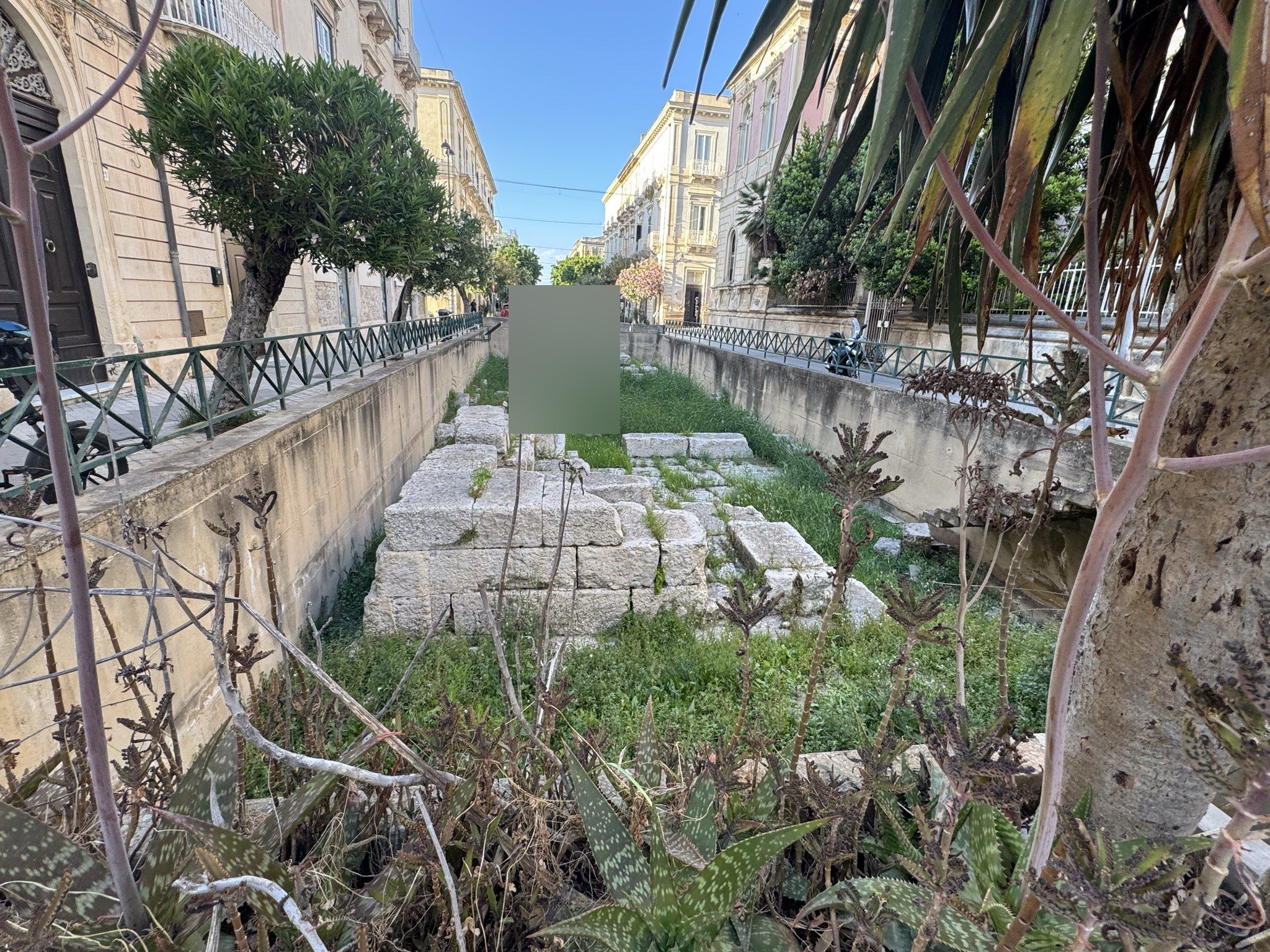 Vista in direzione del centro di Ortigia, con i resti murari in primo piano e la prospettiva della via.