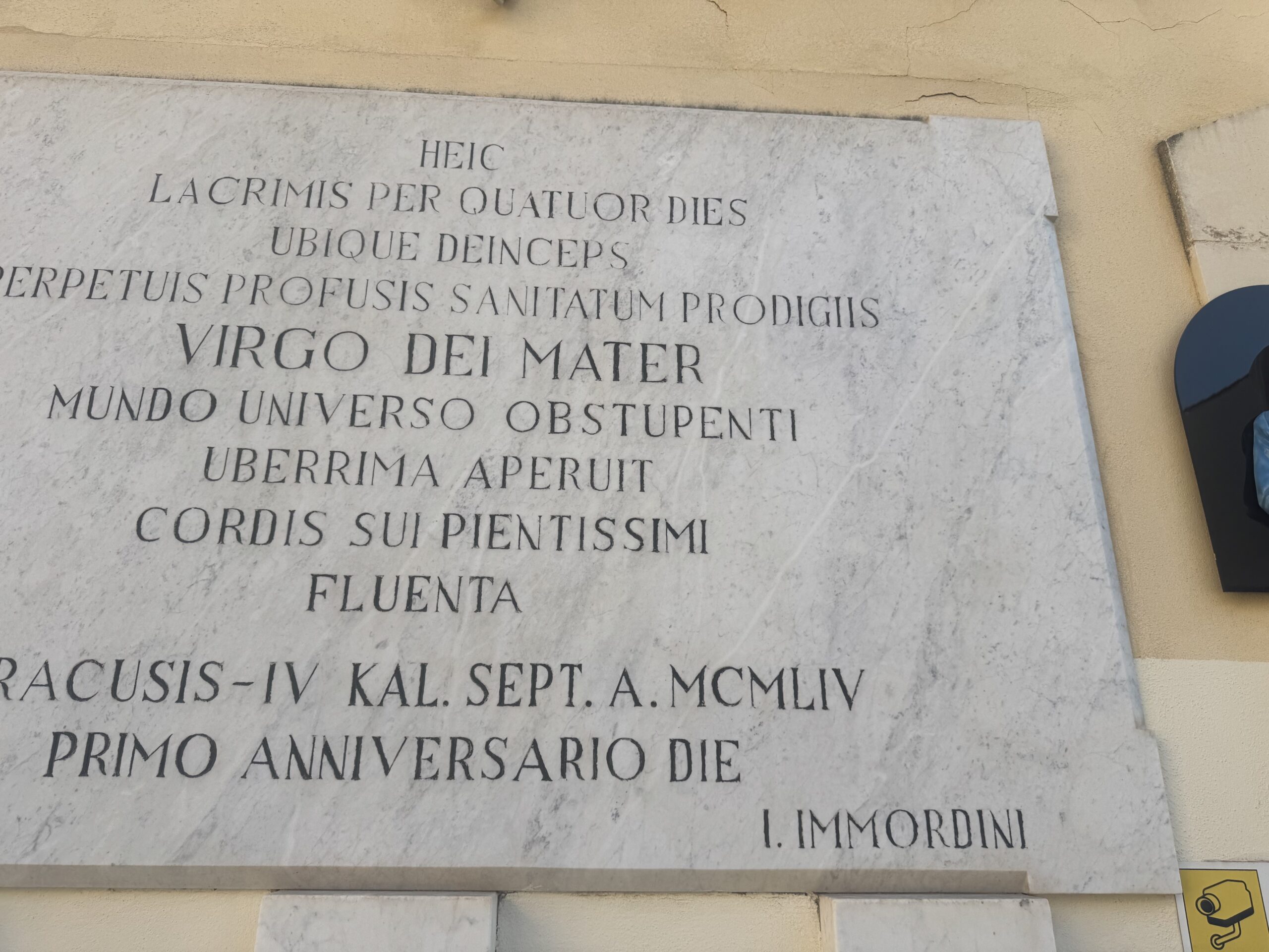 Dettaglio ravvicinato dell'iscrizione latina incisa sulla lapide marmorea, a lettere capitali