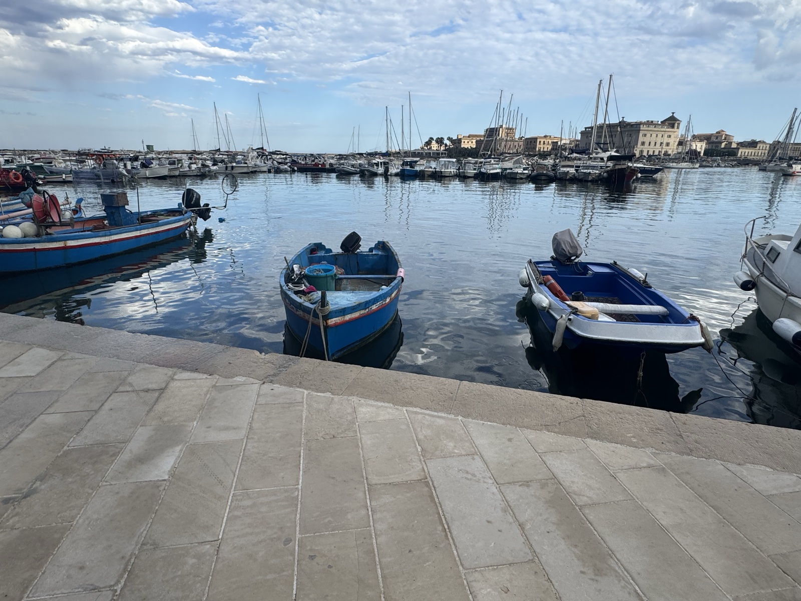 Gradini in pietra chiara che scendono verso l'acqua del Porto Piccolo, della stessa tinta del piano.