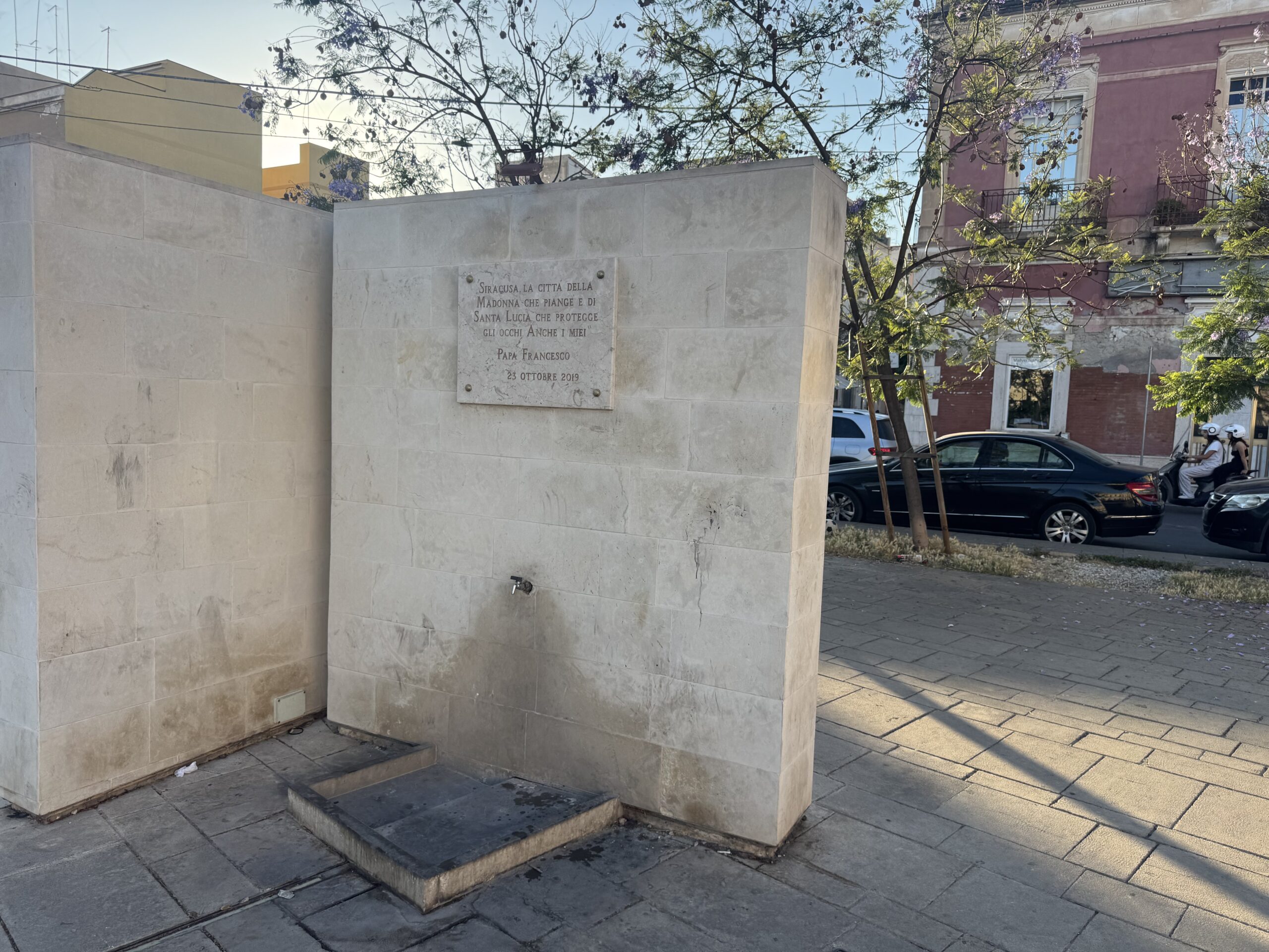 Base posteriore della stele con un elemento d'acqua a raso e griglia, nello spazio pavimentato della piazza