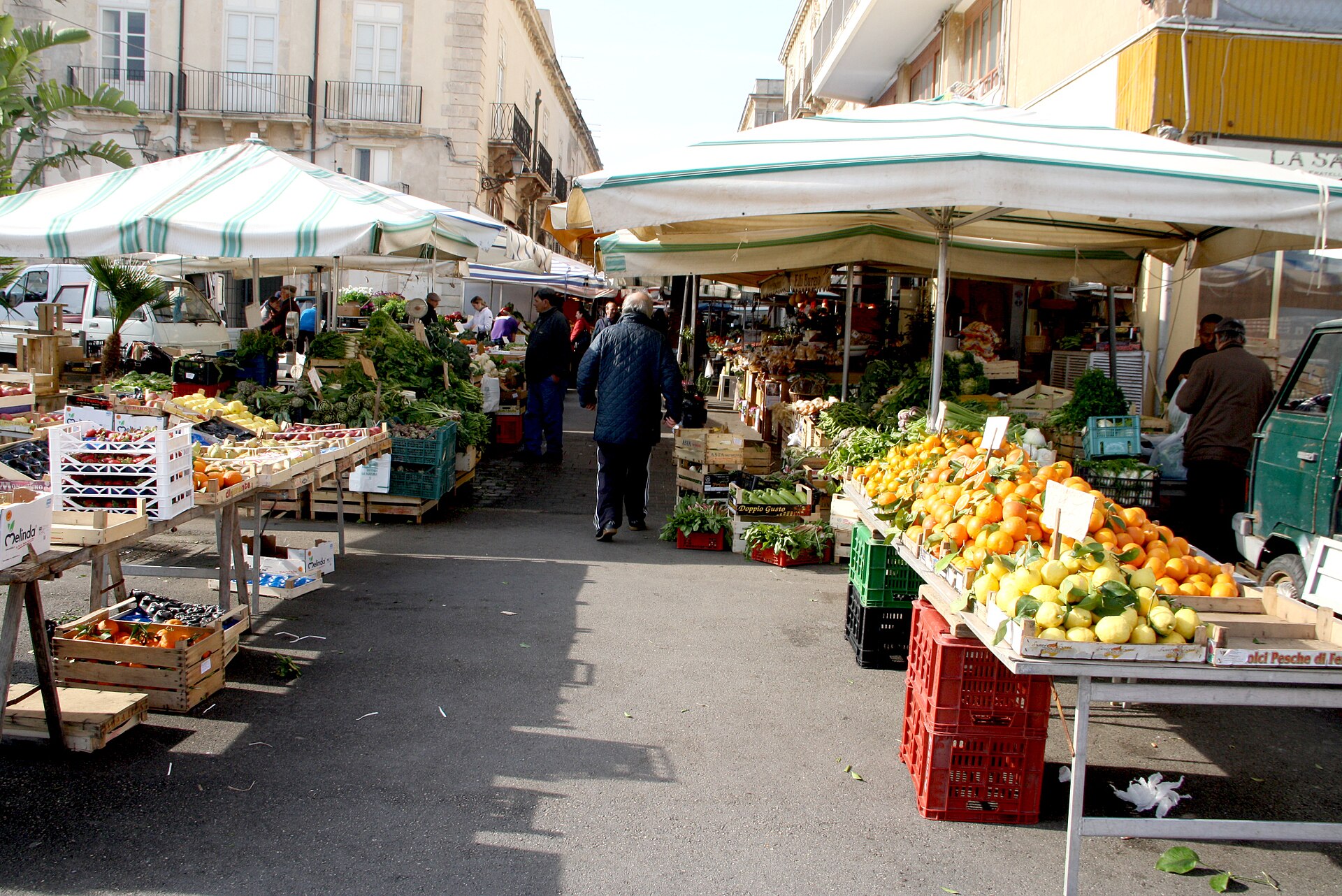 Bancarelle di frutta, verdura e agrumi sotto gli ombrelloni del mercato quotidiano di Ortigia