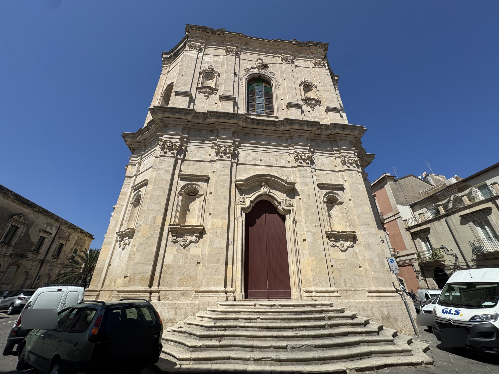 Facciata barocca in pietra chiara su due ordini, con portale ad arco mistilineo, nicchie a conchiglia e finestrone centinato