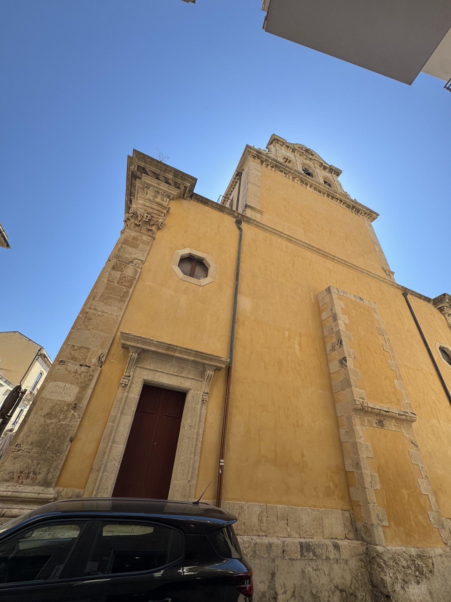 Ripresa verticale della parete laterale ocra sormontata dal campanile a vela in pietra