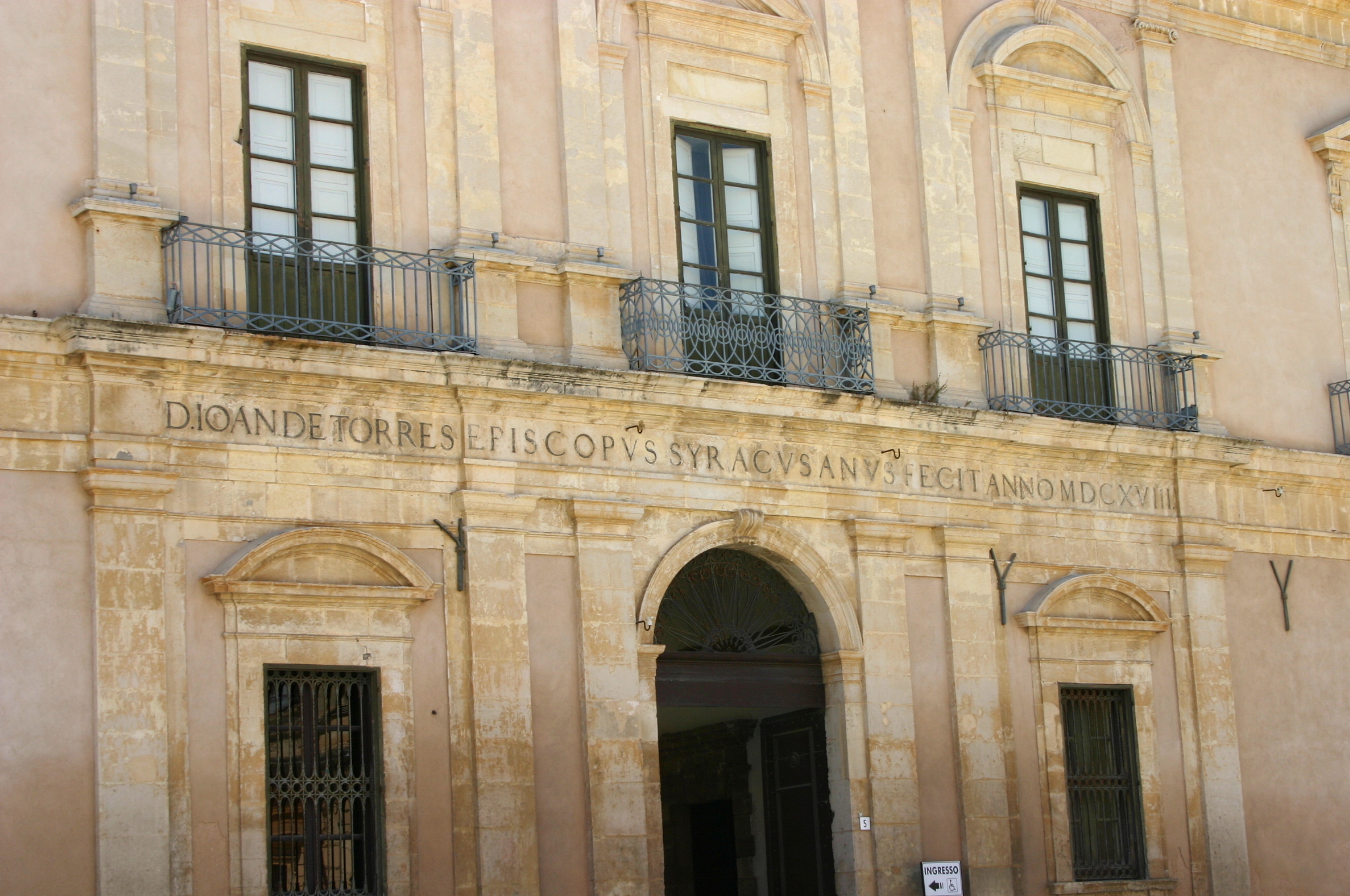 Prospetto del palazzo arcivescovile di Siracusa su piazza Duomo, con portale ad arco e balconi in ferro battuto