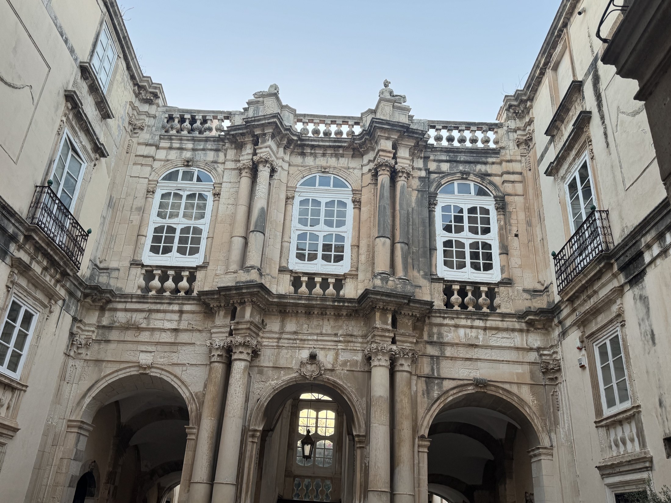 Cortile interno visto dal basso: al piano terra tre arcate su colonne, al piano nobile tre grandi finestre centinate fra colonne e paraste, e in alto una balaustra con vasi e due statue