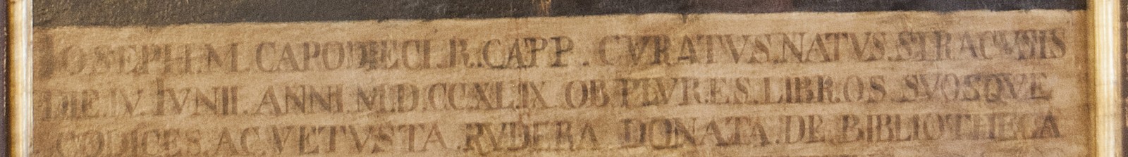Cartiglio dipinto con iscrizione latina che ricorda la nascita di Capodieci il 4 giugno 1749 e le sue donazioni alla biblioteca e al museo